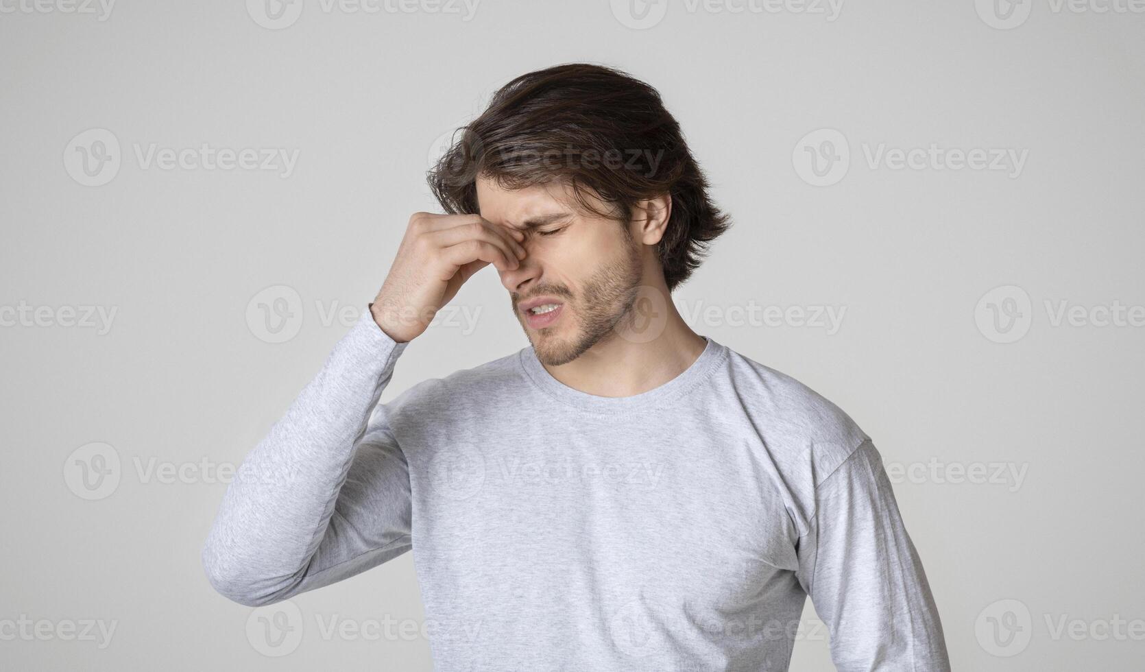 Runny nose or sinusitis concept. Handsome guy holds nose bridge and suffers from pain photo