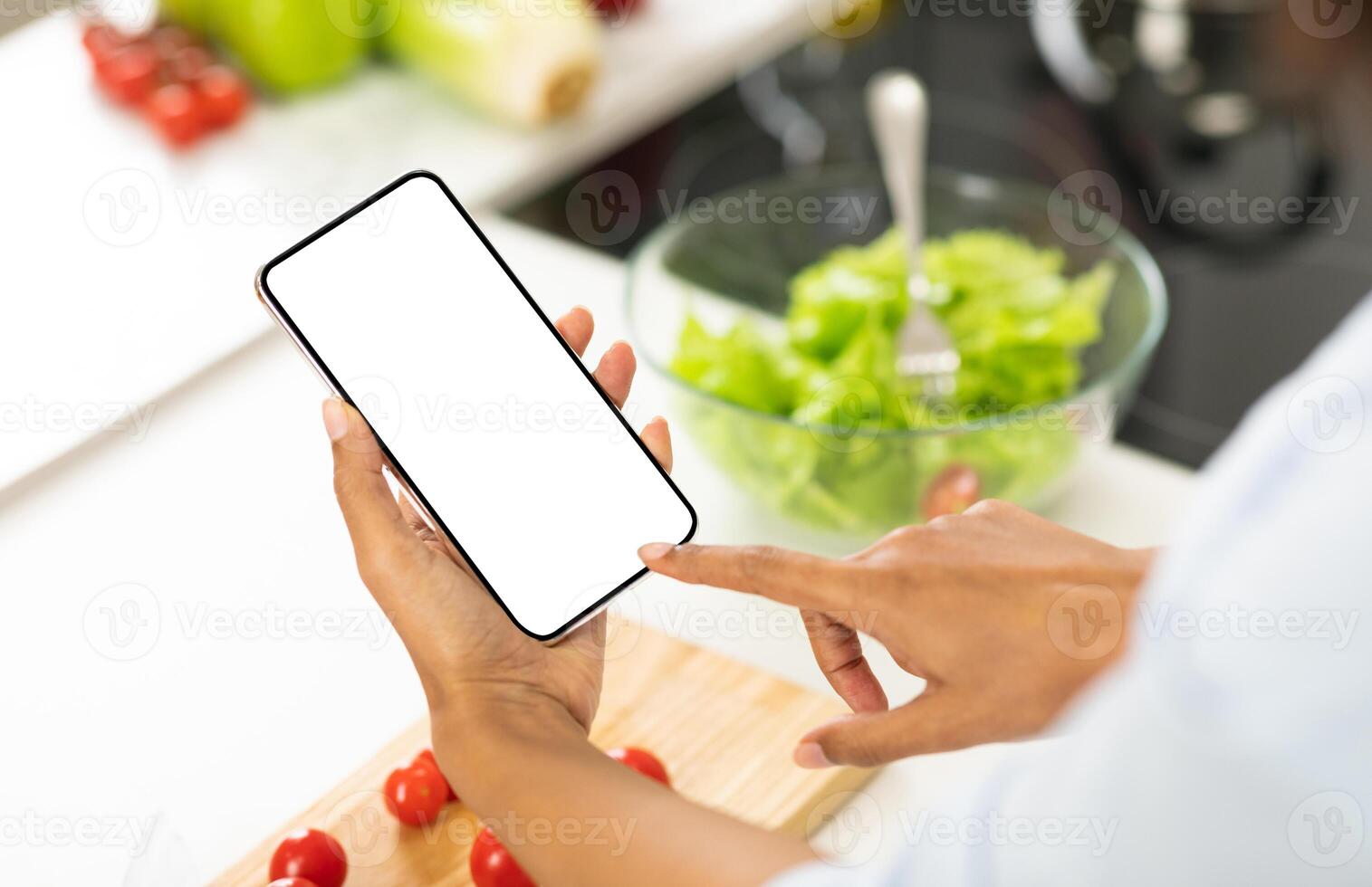 Healthy Food And Diet Planning Concept. Black girl using smartphone with blank screen in the kitchen, mock up photo