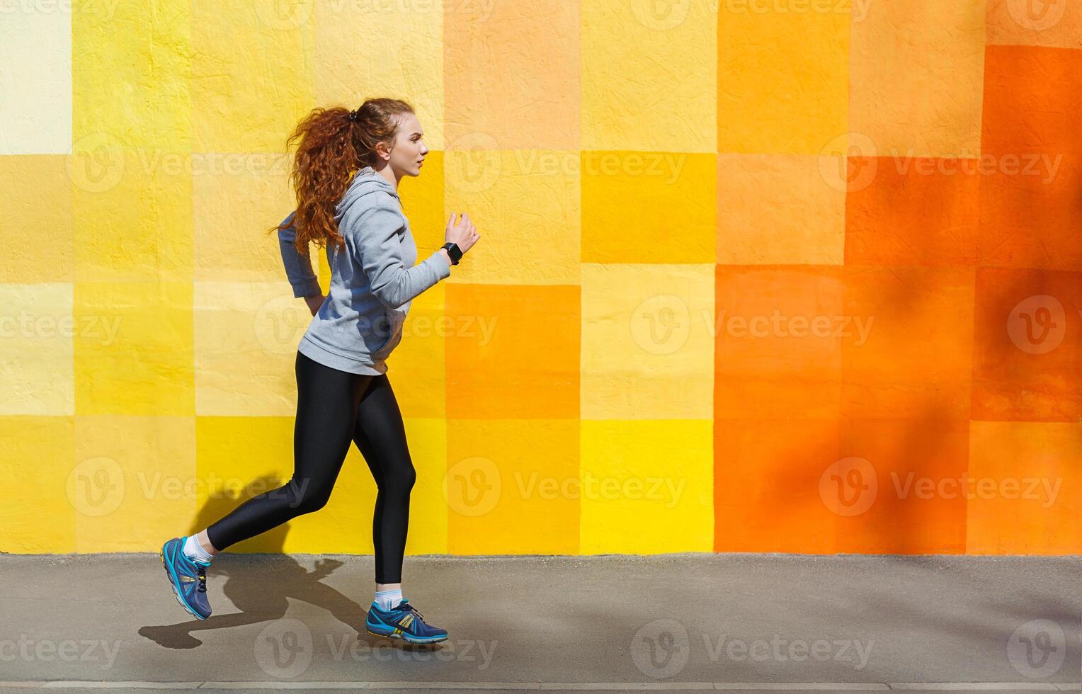 Side view of female athlete running against bright colorful graffiti wall, copy space photo