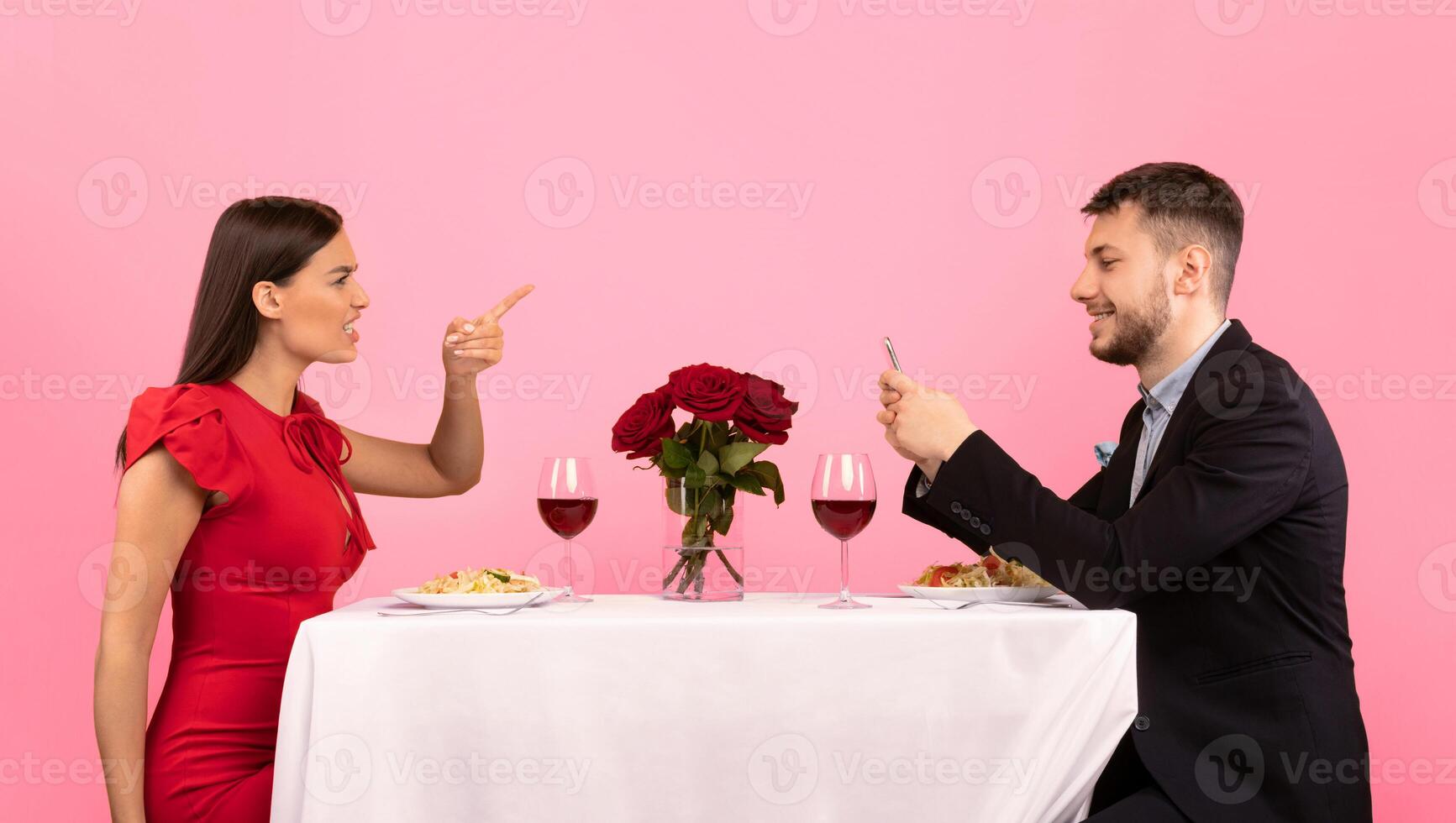Jealousy In Relationship. Jealous Girlfriend Shouting At Boyfriend While He Using Mobile Phone Suspecting Affair Over Yellow Studio Background. Panorama photo
