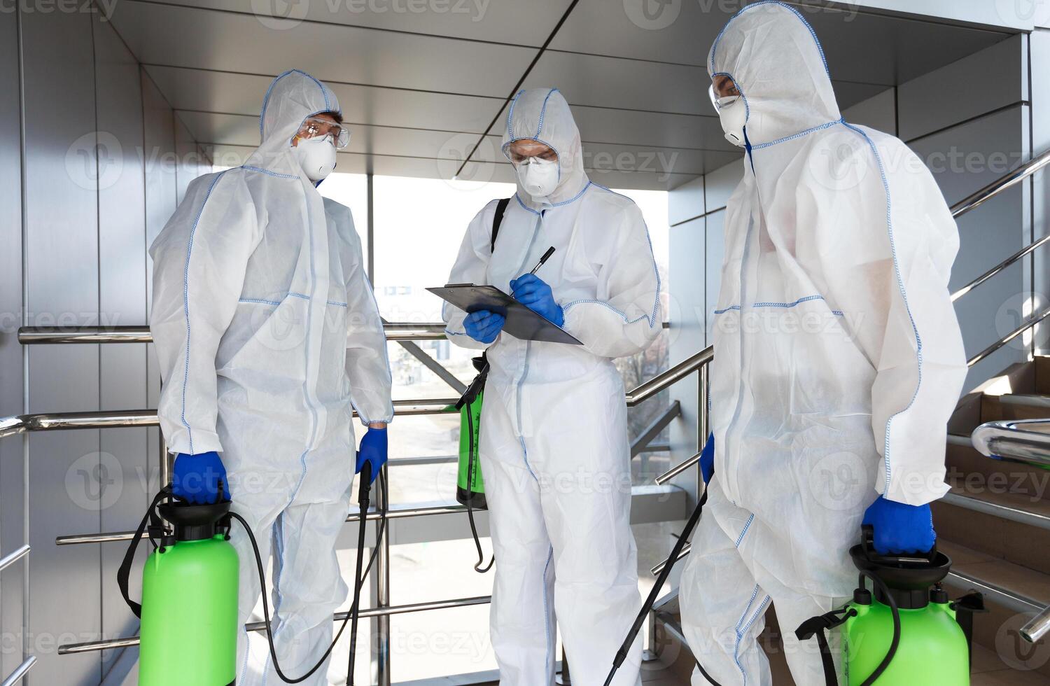 Men in virus protective suits disinfecting indoor accommodation, pandemic health risk, coronavirus photo