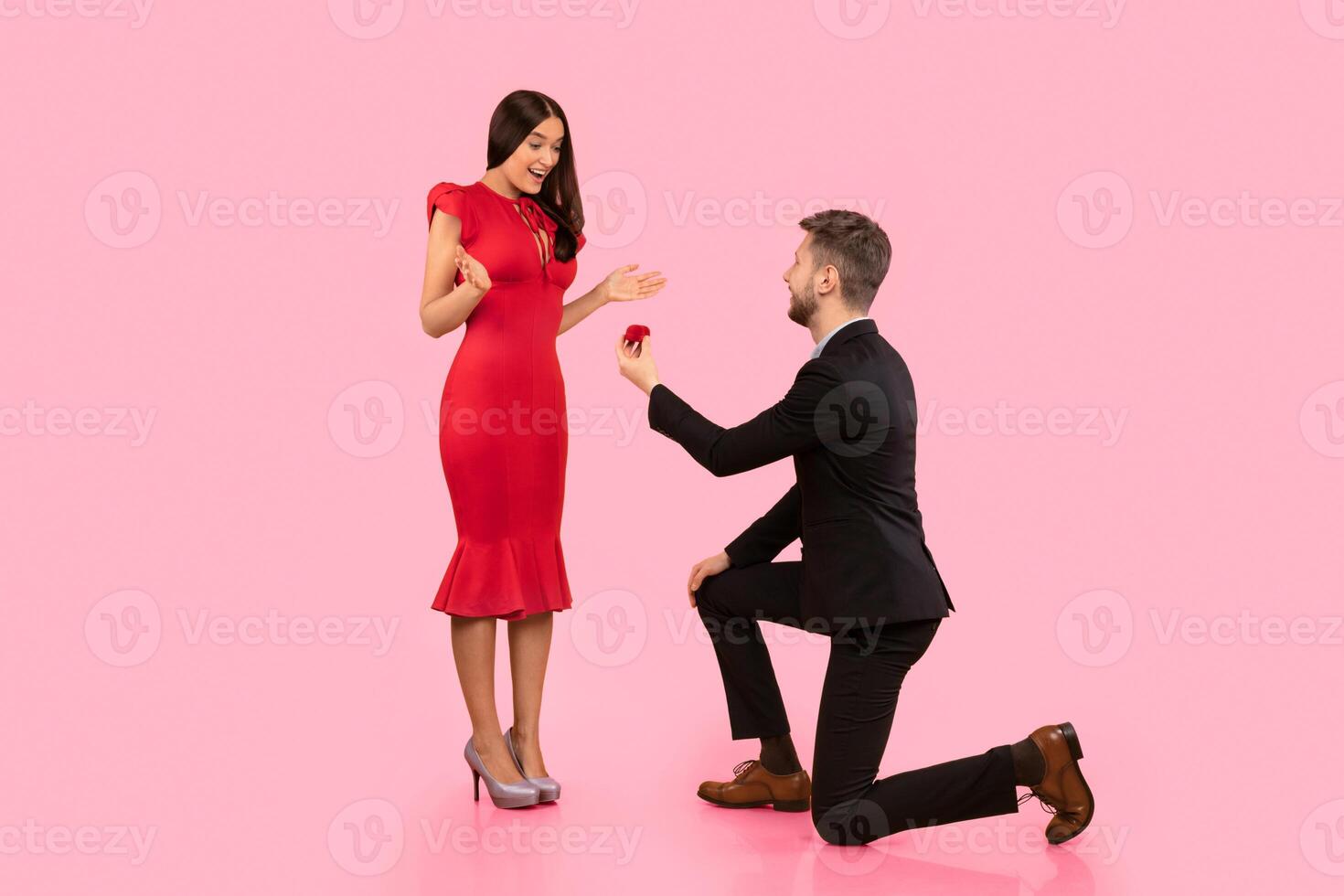 Marry Me. Boyfriend Proposing Standing On Knee Giving Engagement Ring To Girlfriend On Yellow Background. Studio Shot photo