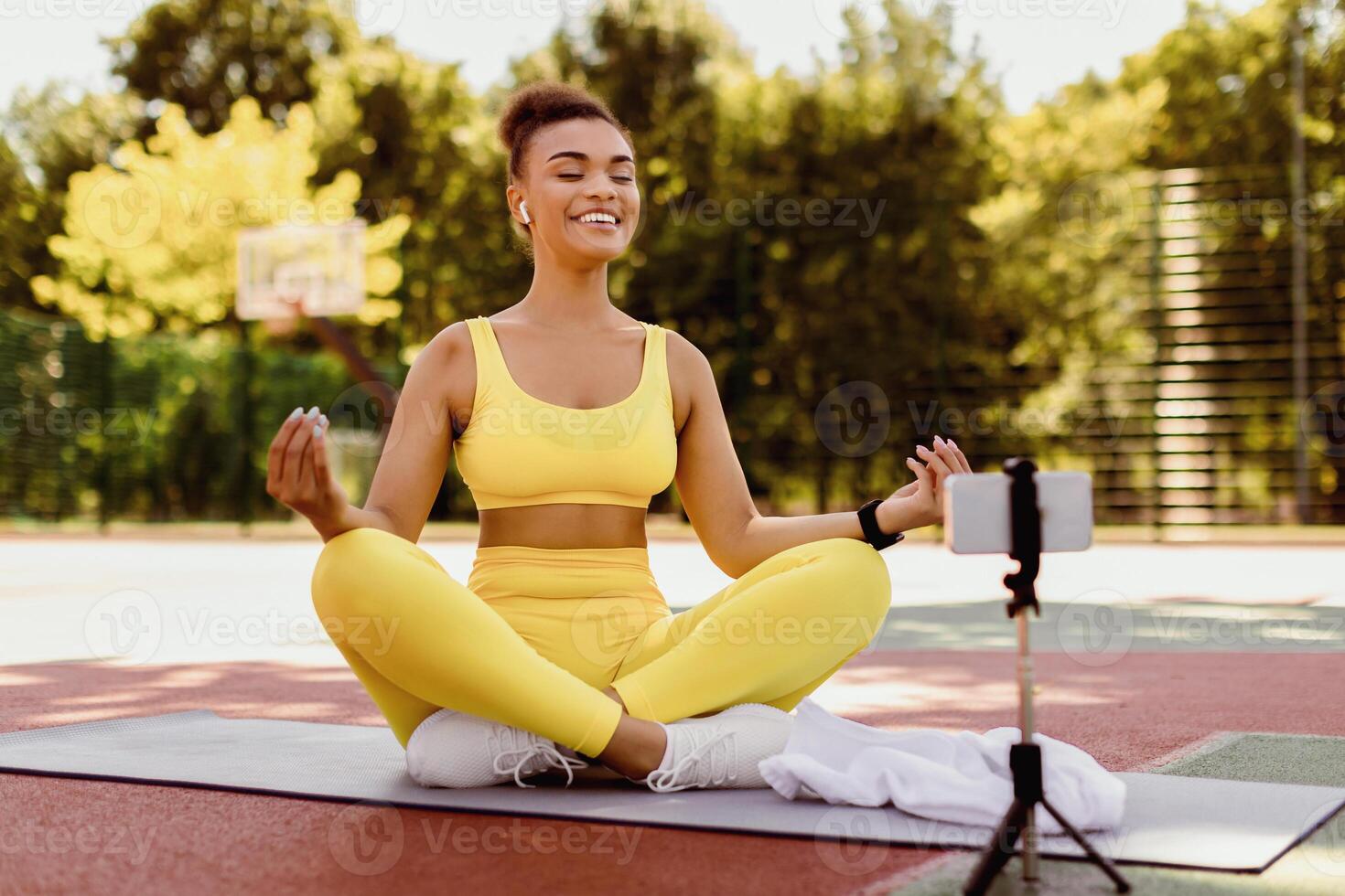 Remote Distance Online Meditation Class. Happy Young Black Lady Streaming Yoga Lesson Outside, Laughing Sporty Female Using Smartphone On Tripod, Watching Or Shooting Content For Fitness Blog photo