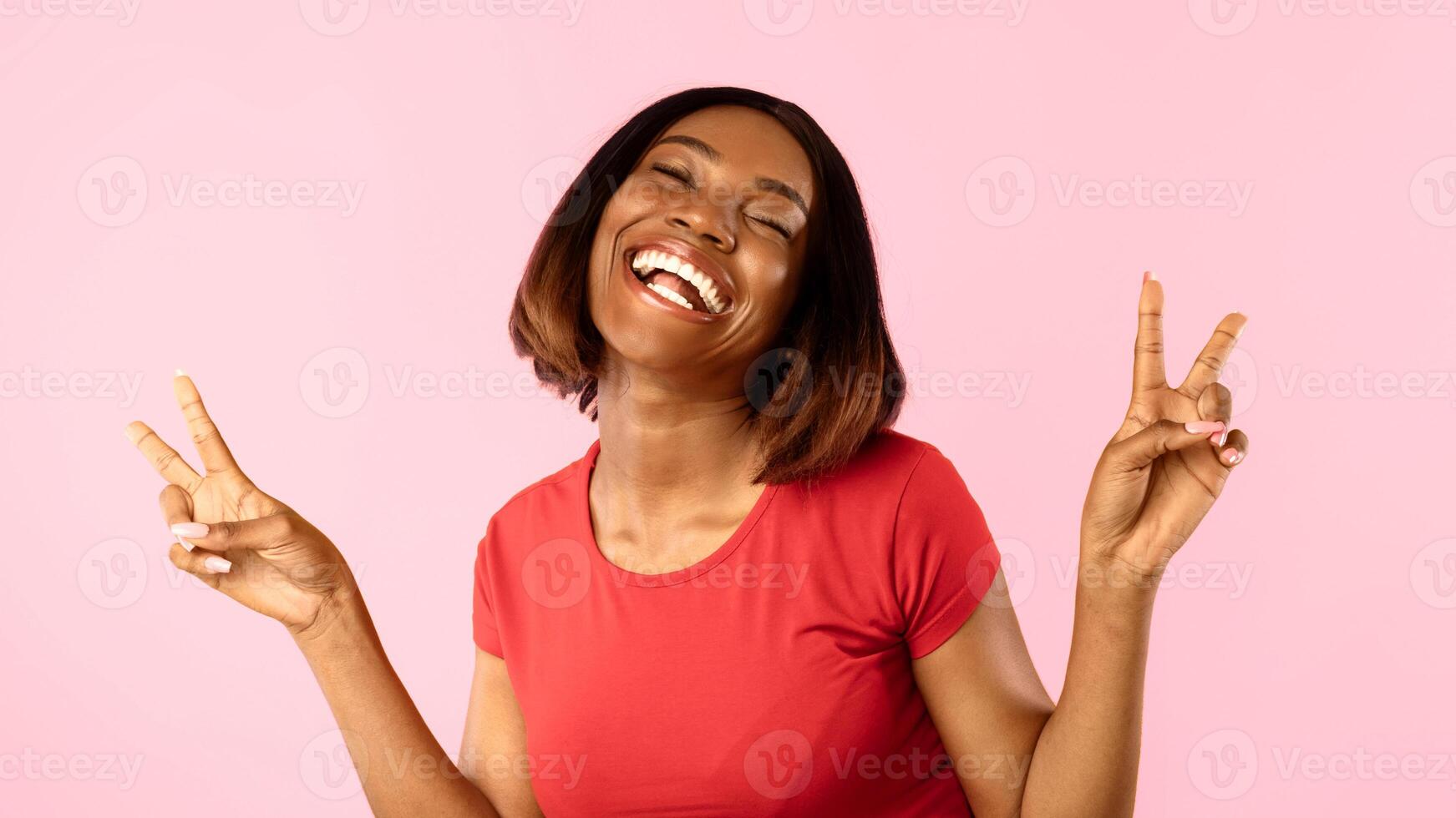 Happy Black Lady Gesturing Victory Symbol With Both Hands Smiling To Camera Standing On Yellow Studio Background. Portrait Of Cheerful Woman Showing V-Sign, Peace Gesture Panorama photo