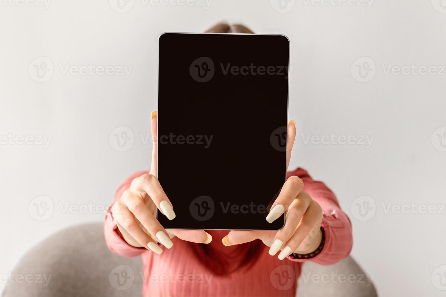 Millennial woman showing digital tablet with blank screen on white studio background, mockup for website or app design. Young lady presenting touch pad with space for online advertisement, closeup photo