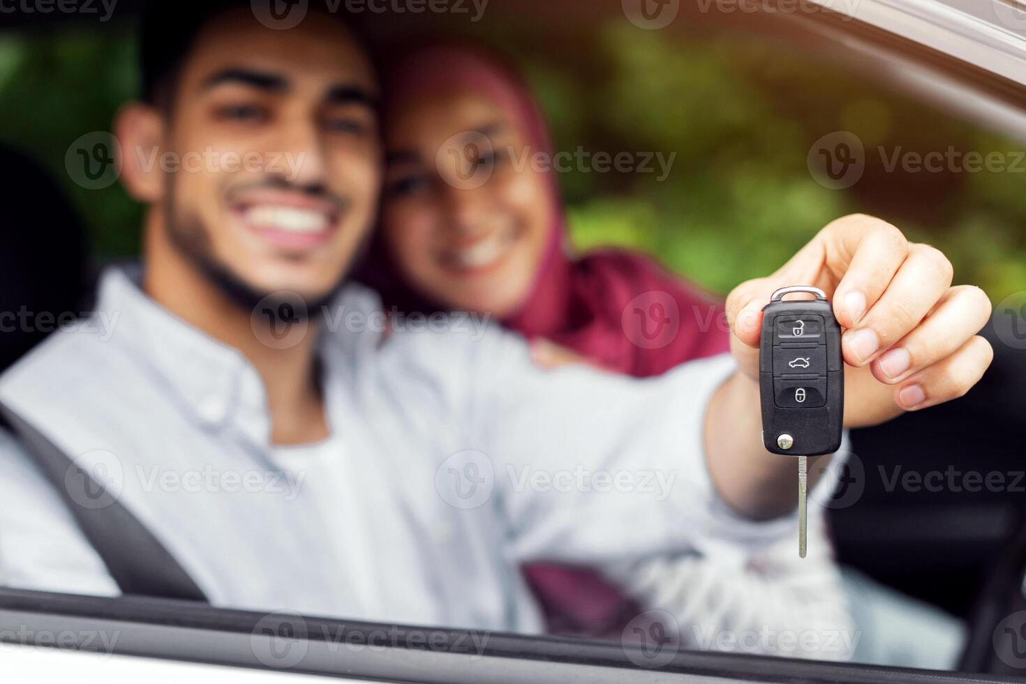 Test drive transport. Glad happy millennial arab woman in hijab and man show keys from new car, enjoy to purchase, couple have fun together, blurred. Buying own auto, credit, ad and offer, copy space photo