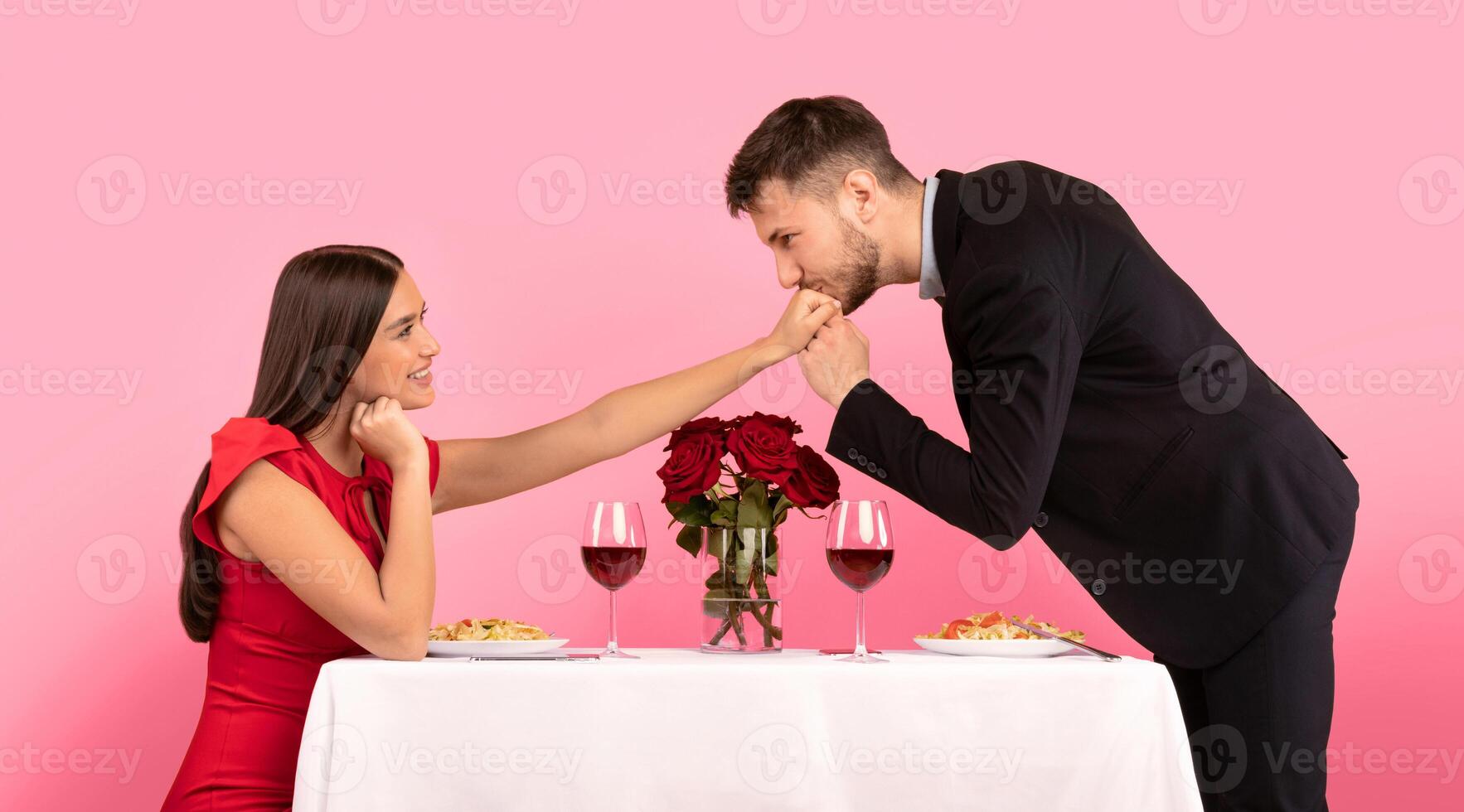 Romantic Relationship. Boyfriend Kissing Girlfriend's Hand Dating Sitting At Restaurant Table In Studio On Yellow Background. Panorama photo