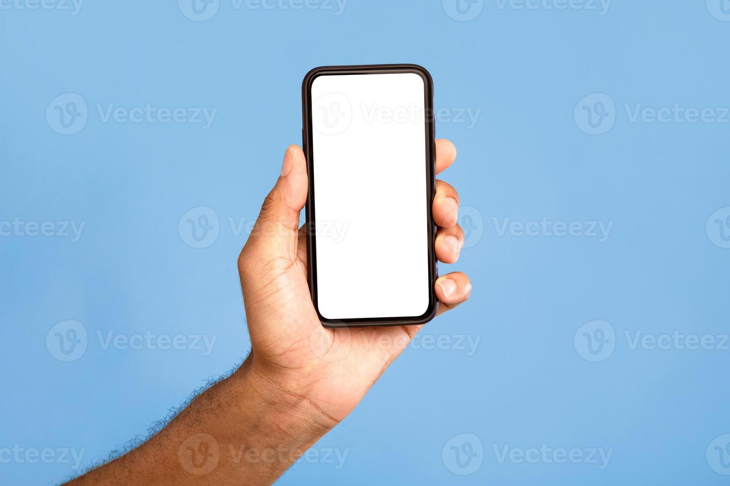 Amazing mobile app. Unrecognizable African American man showing cellphone with mockup, advertising application or website, promoting online product or service over blue background, closeup photo