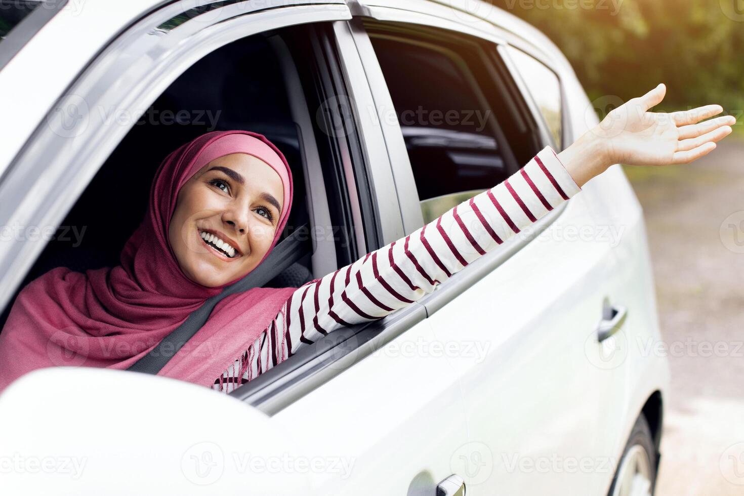 Rear view of little boy leaning out of car window and trying to catch wind with outstretched hand, small male child enjoying summer weather and automobile ride, on the move shot, closeup photo