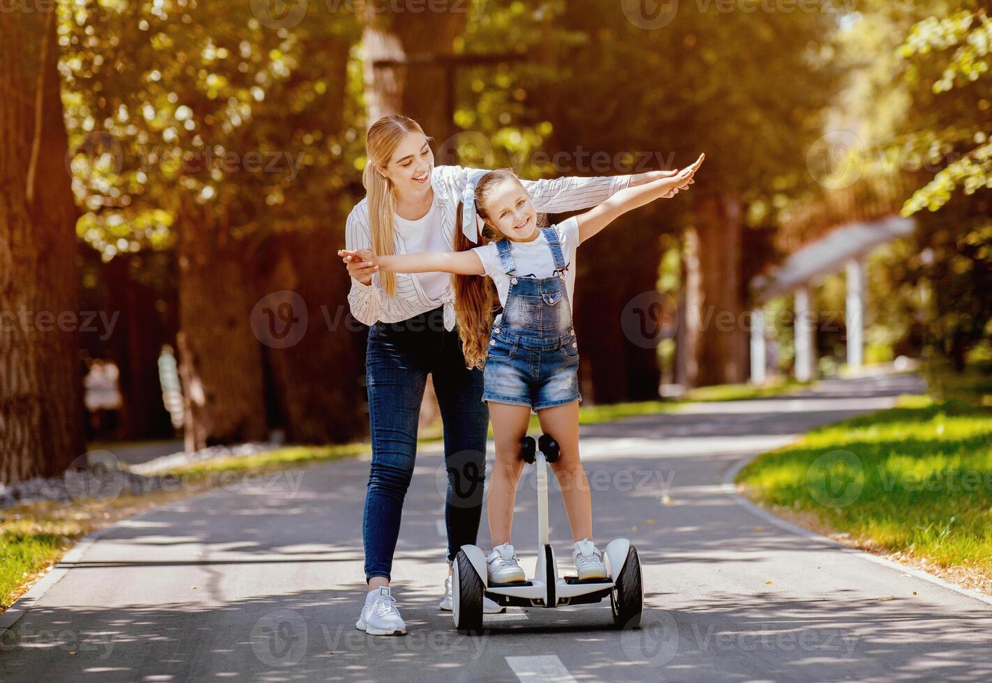 Mom Teaching Daughter To Ride Segway Having Fun In City Park Outdoors. Weekend Leisure Concept. Free Space photo
