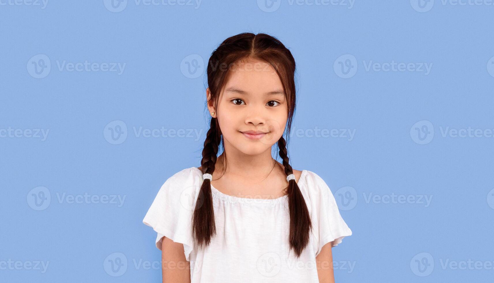 Cute Asian Kid Girl Posing Smiling To Camera Standing Over Purple Background. Studio Shot photo