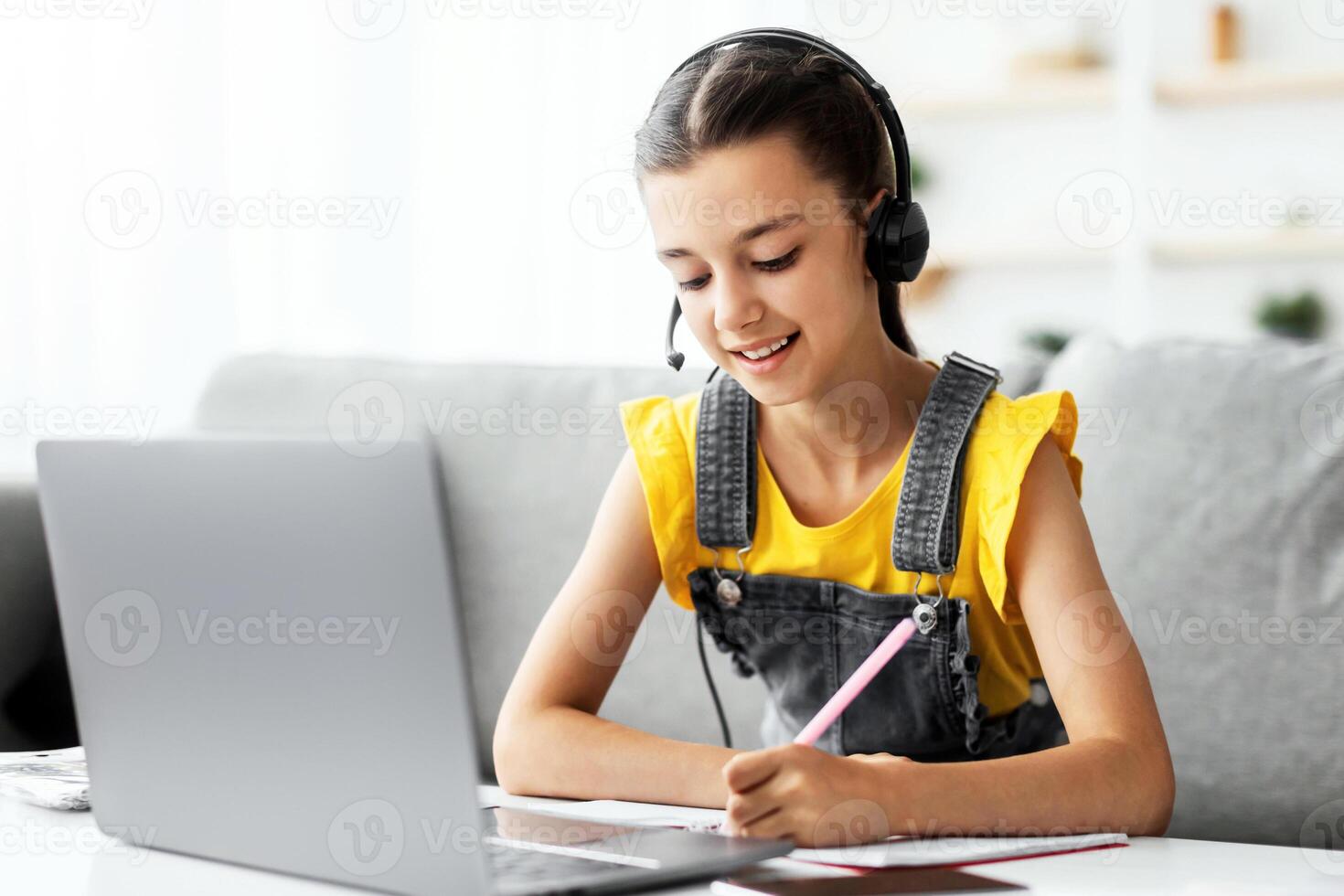 Homeschool little young girl student in headset learning during virtual internet online class with school teacher having remote meeting. Pupil studying foreign language or math photo