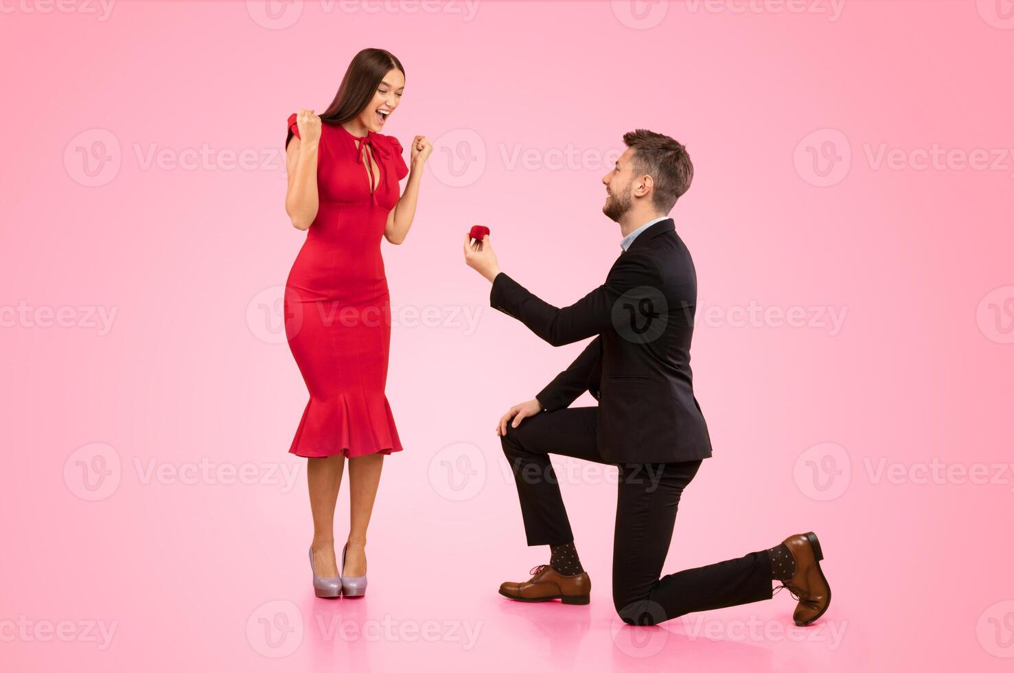 She Said Yes. Man Proposing To Girlfriend Offering Her Ring In Box Standing On Knee Over Yellow Background In Studio photo