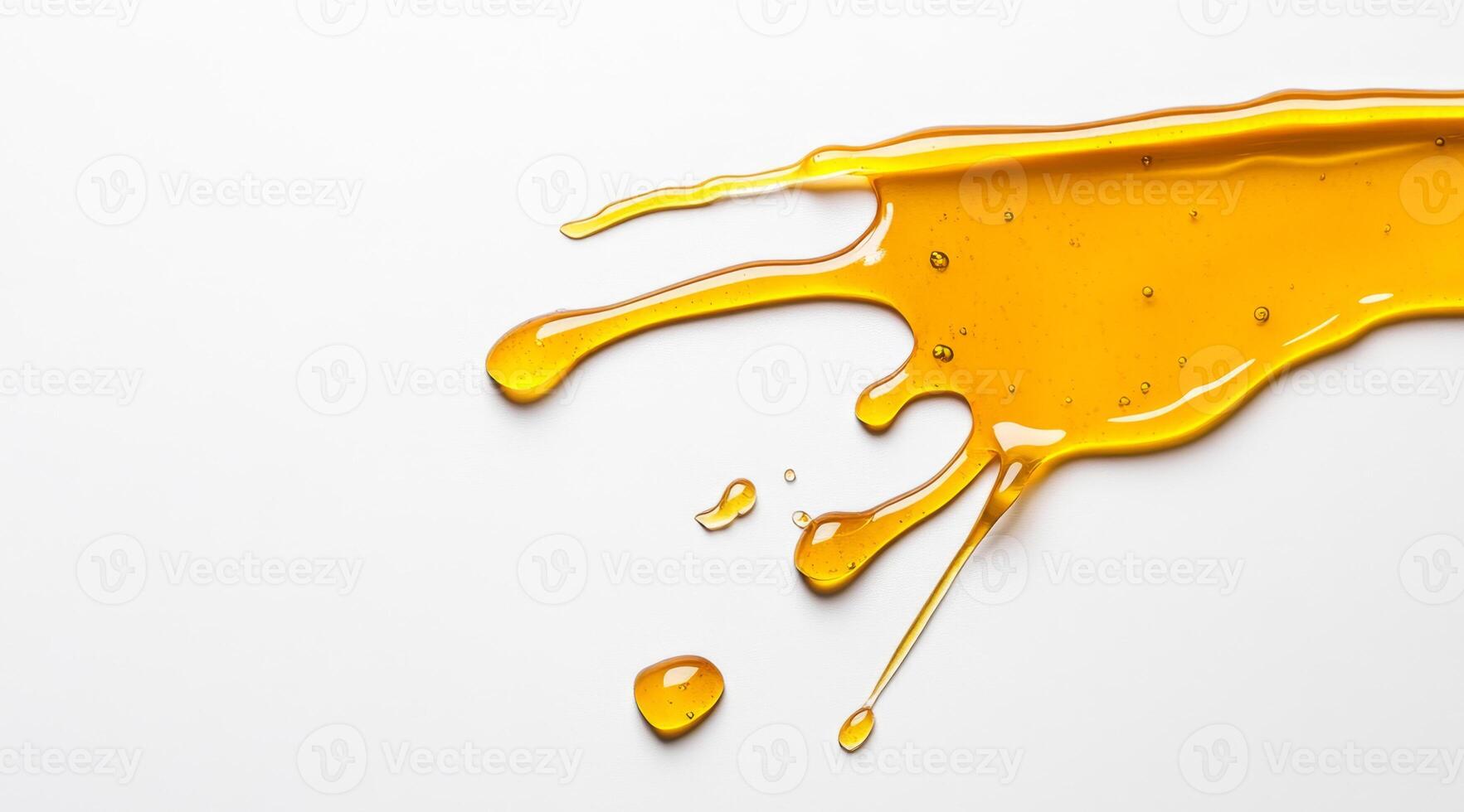 Golden honey is splashed across a clean white surface, creating an appealing visual of liquid motion. The vibrant droplets showcase the smooth texture and rich color of the honey. photo