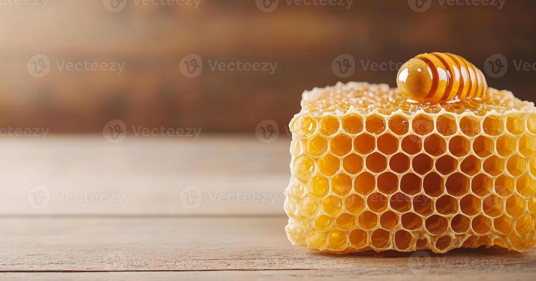 Golden honey rests atop a piece of fresh organic honeycomb, showcasing intricate hexagonal patterns. The warm wooden table enhances the natural beauty of this beekeeping product. photo