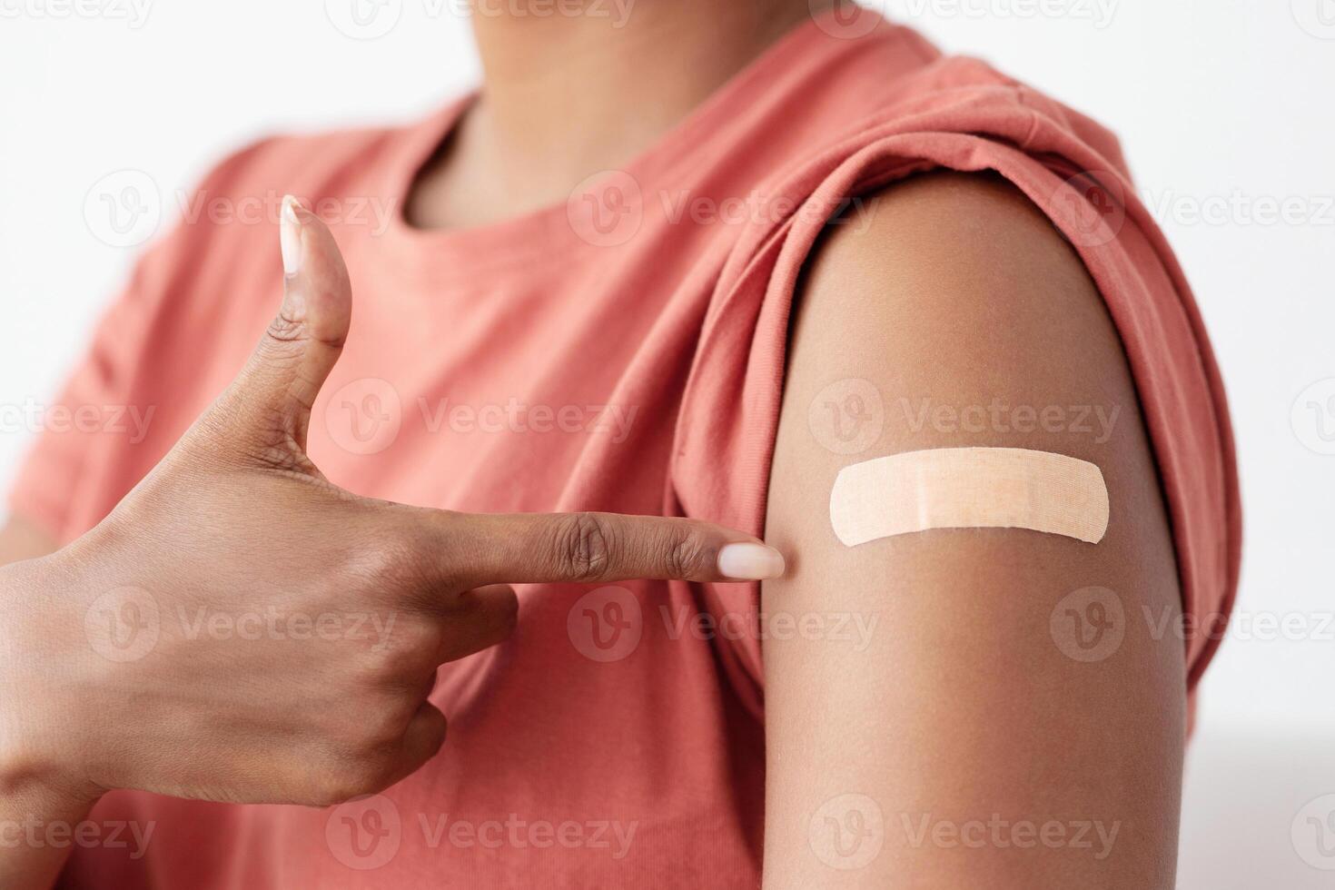 Unrecognizable patient black woman pointing at medial band on her arm, got vaccinated against coronavirus while COVID-19 pandemic, cropped. Immunization, vaccination concept photo