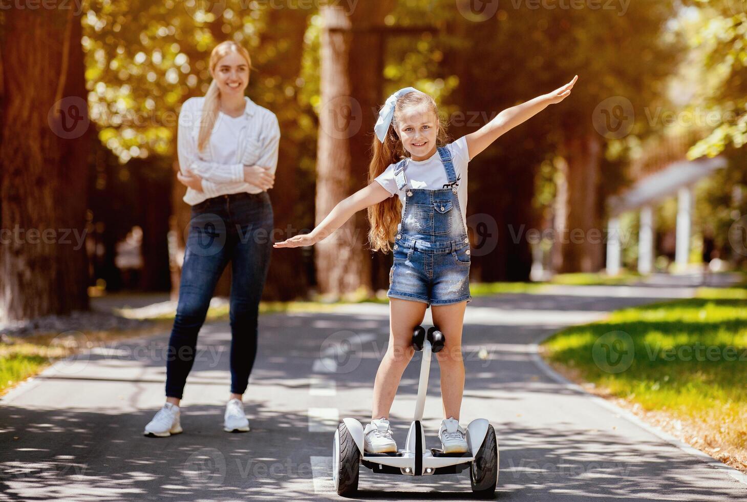 Little Girl Riding Segway Having Fun Spending Weekend With Mother In Park Outdoor. Selective Focus photo