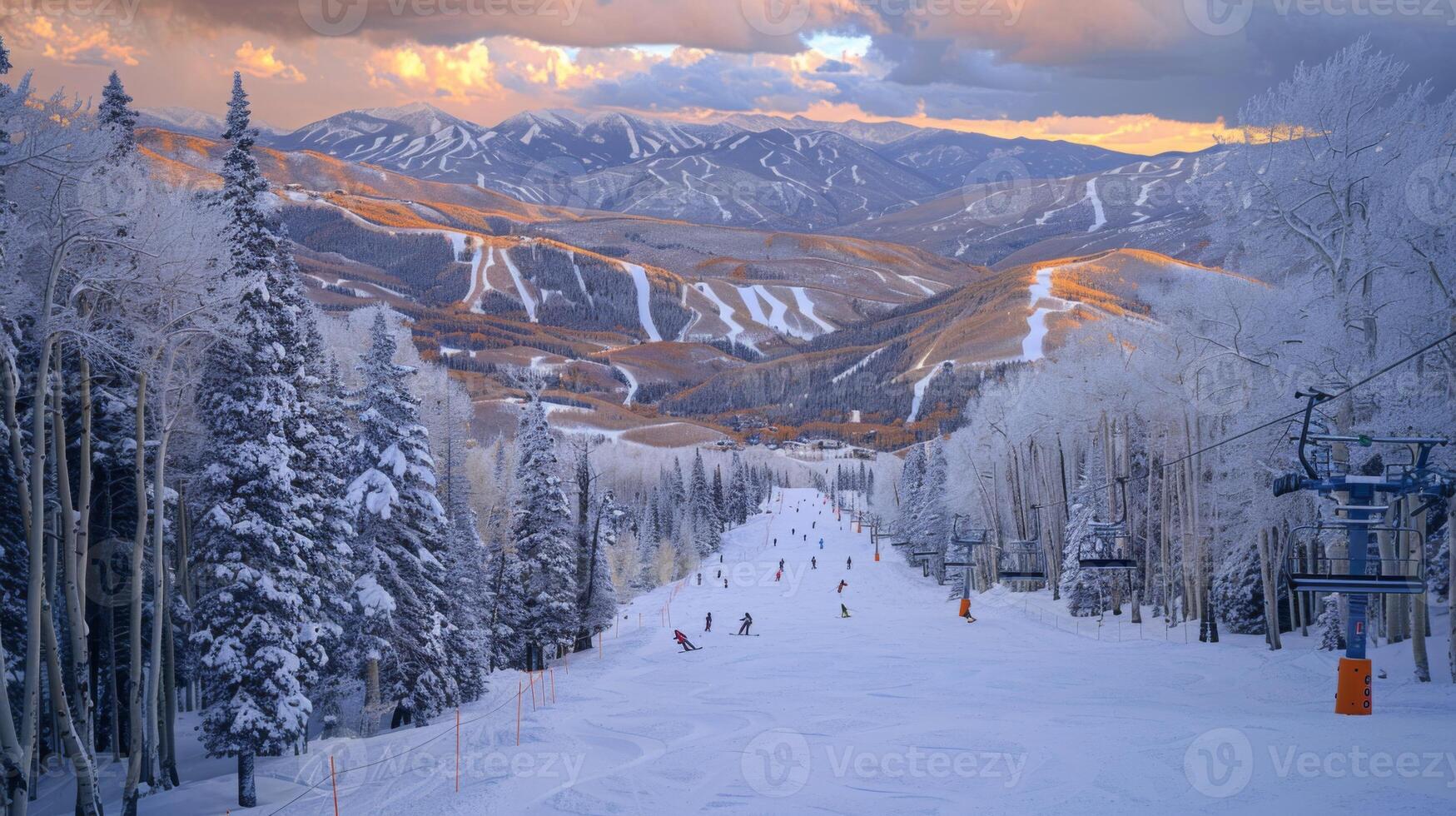 Skiers navigate down a snowy slope surrounded by tall trees, with majestic mountains in the background illuminated by a colorful sunset, creating a serene winter atmosphere. photo