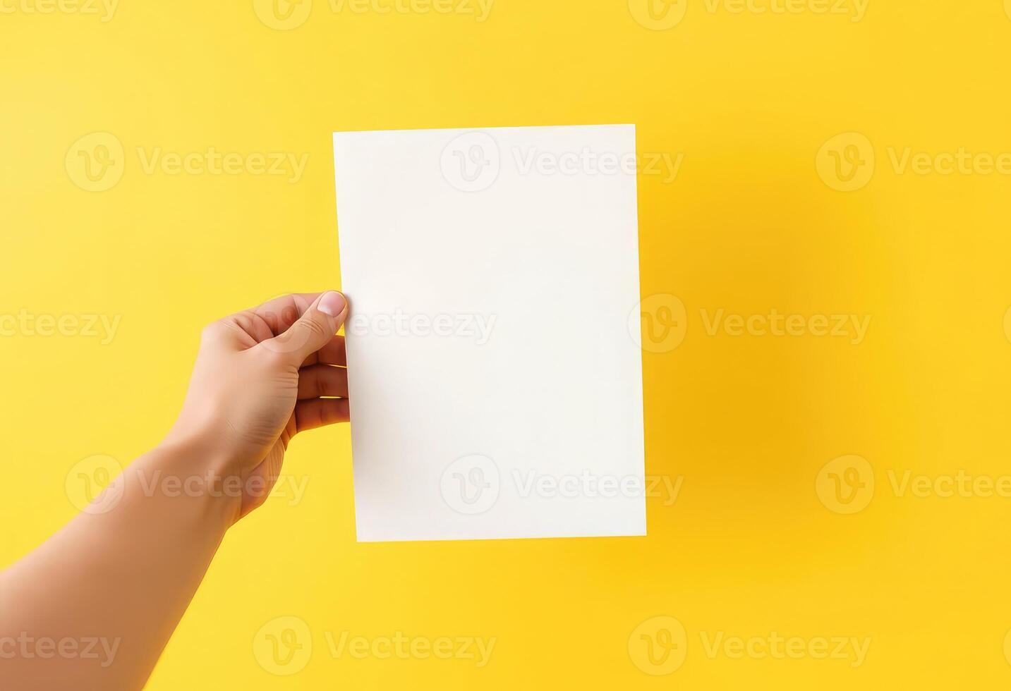 A hand holding a blank white cover magazine mockup against a vibrant yellow background photo