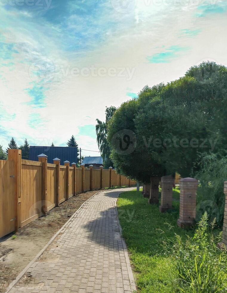 A walkway with a wooden fence and brick walkway photo