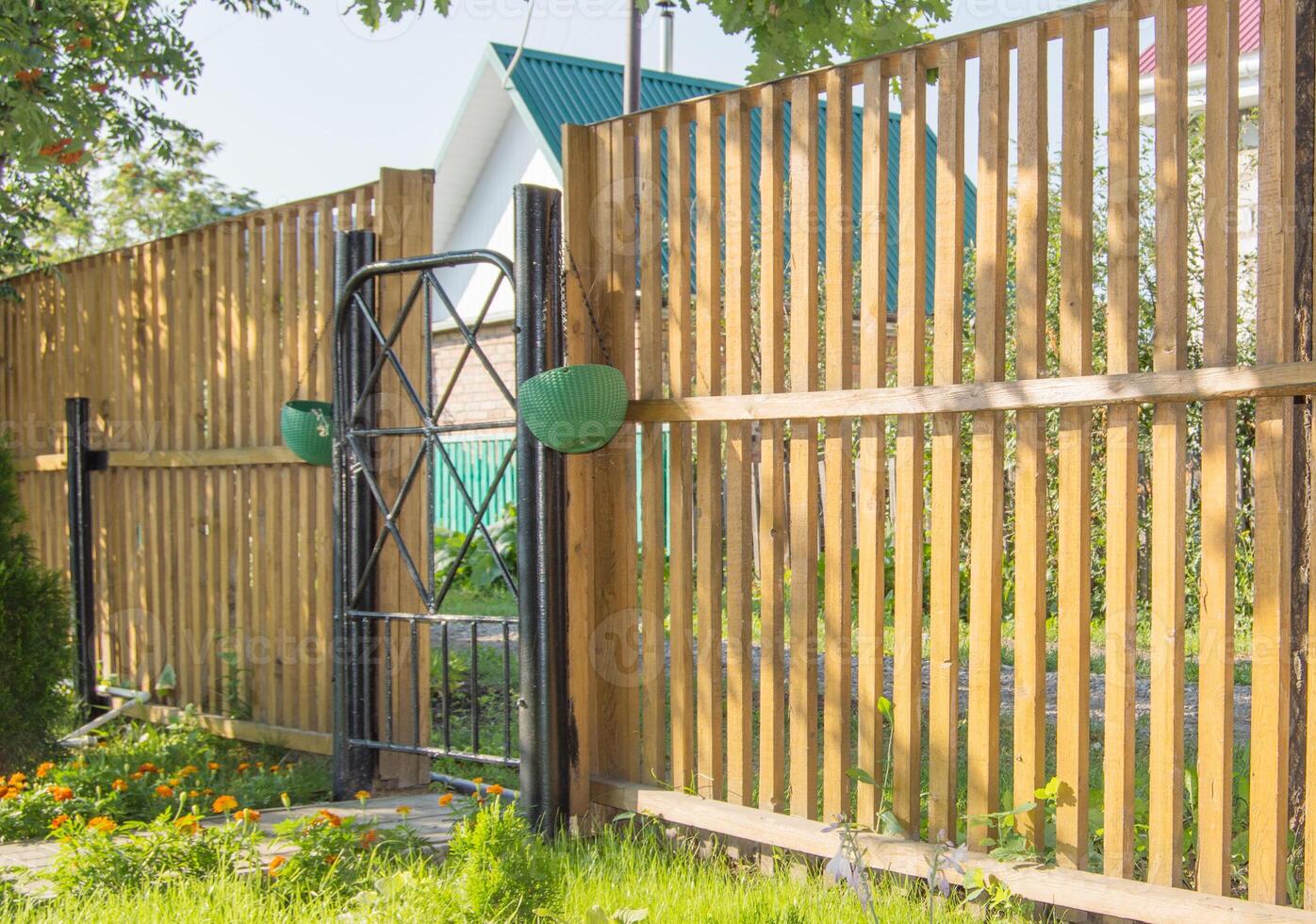 A wooden fence with a gate and a green plant photo
