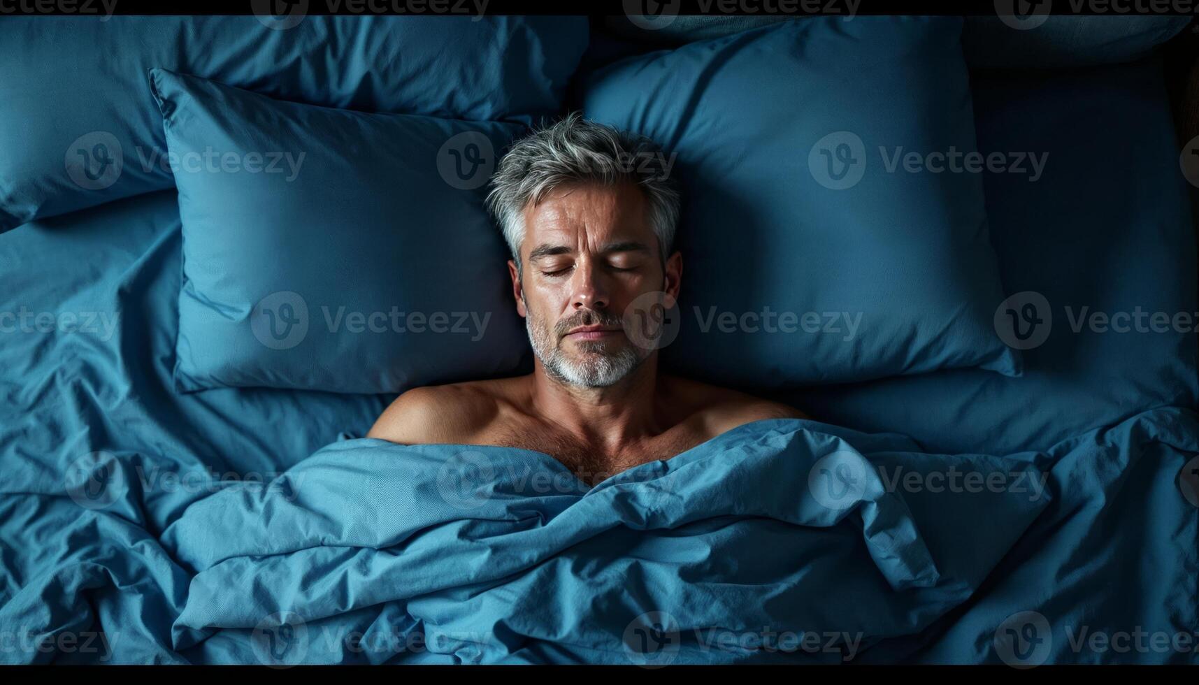 A man sleeping in bed with blue sheets photo