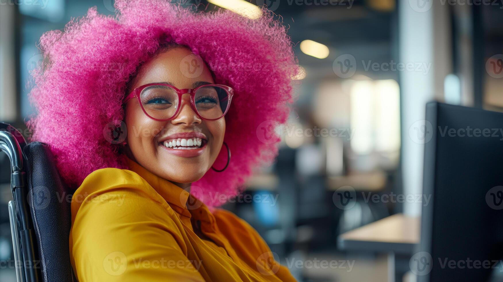 A joyful black woman with vibrant pink afro hair smiles while working in an inclusive office setting, showcasing diversity and positivity photo