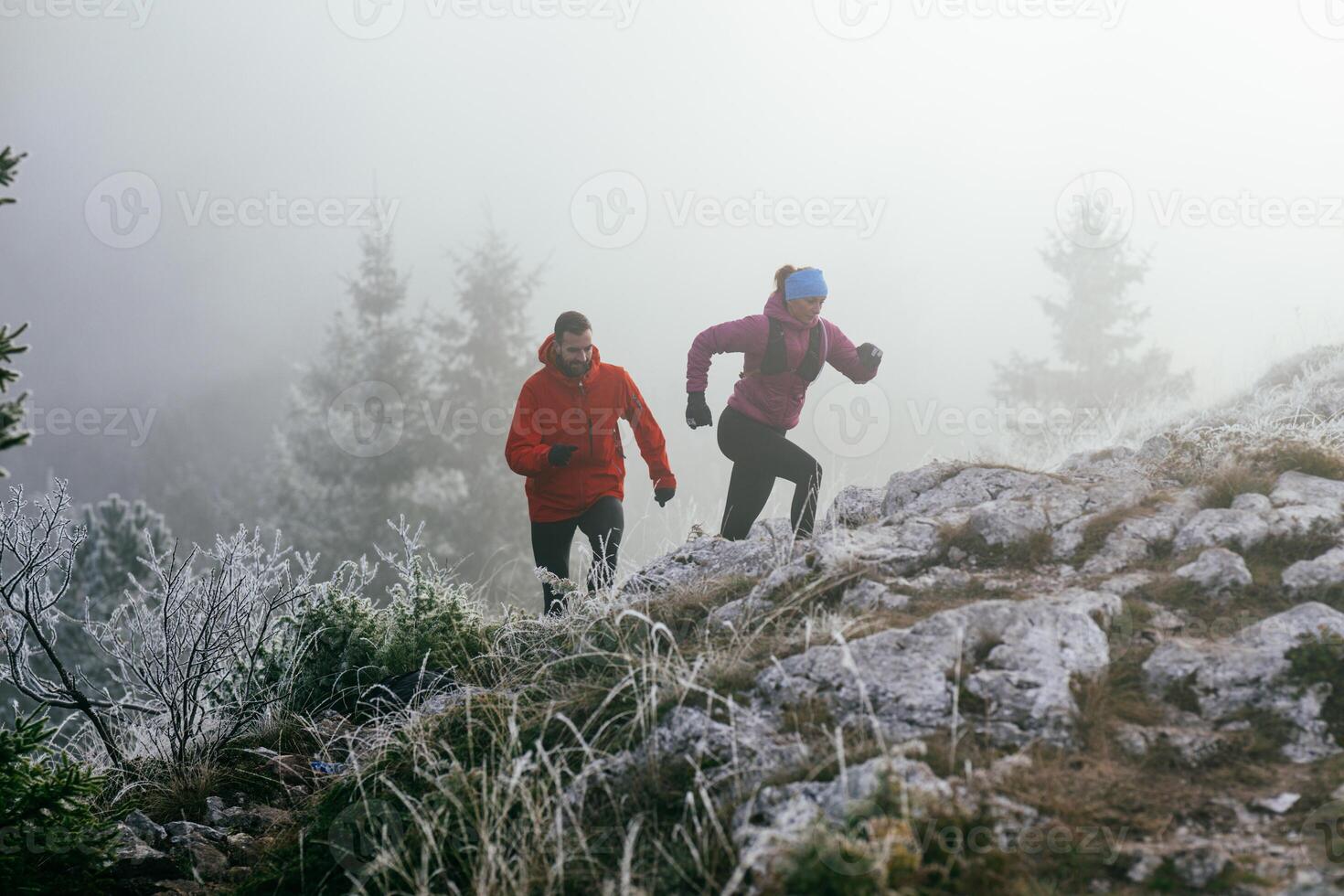 Trail running couple man and woman running on a mountain path photo
