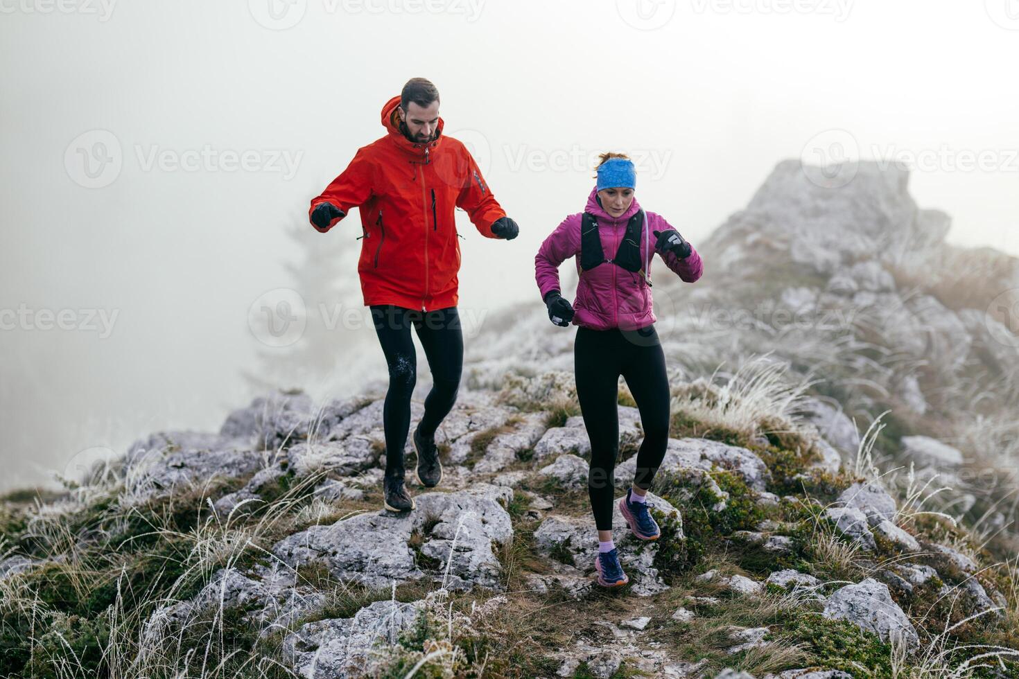 Trail running couple man and woman running on a mountain path photo