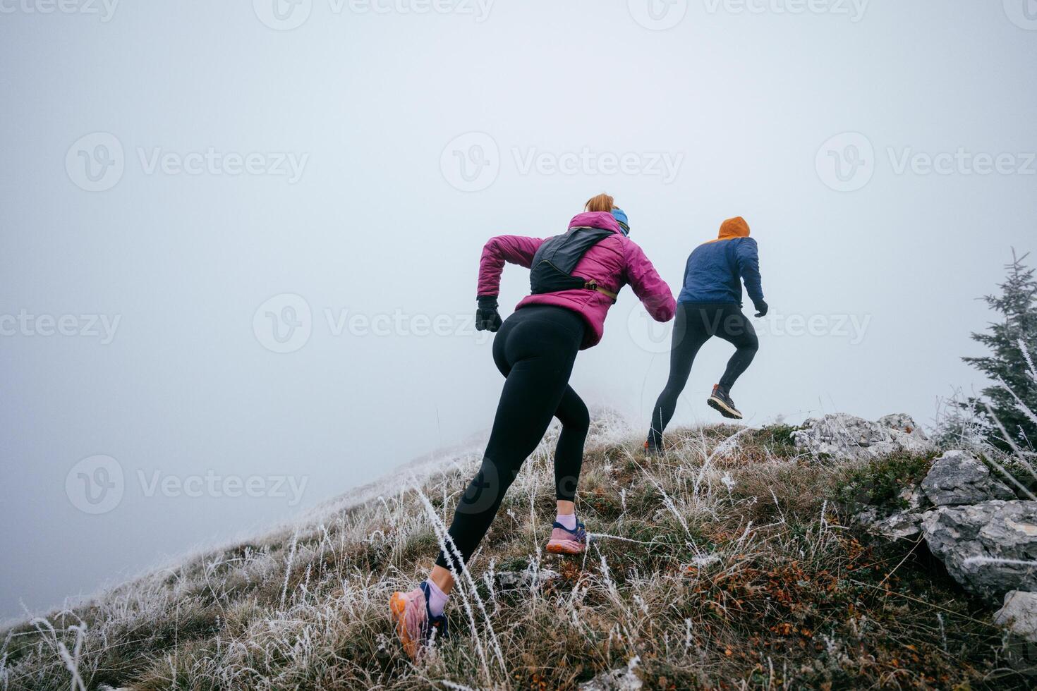 Trail running couple man and woman running on a mountain path photo