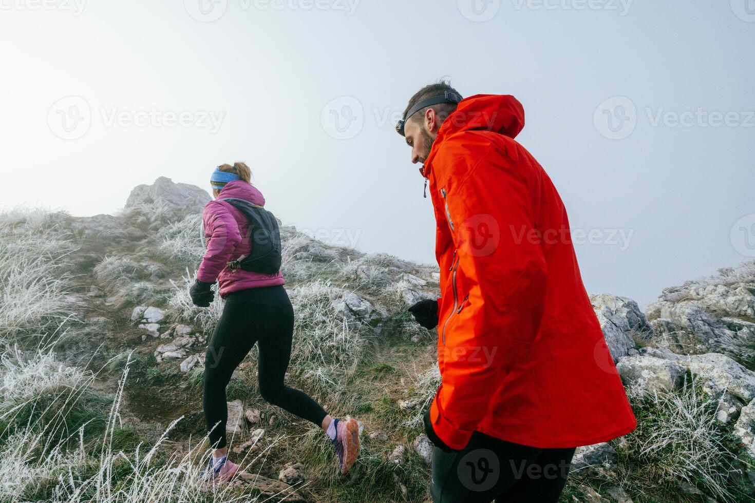 Trail running couple man and woman running on a mountain path photo