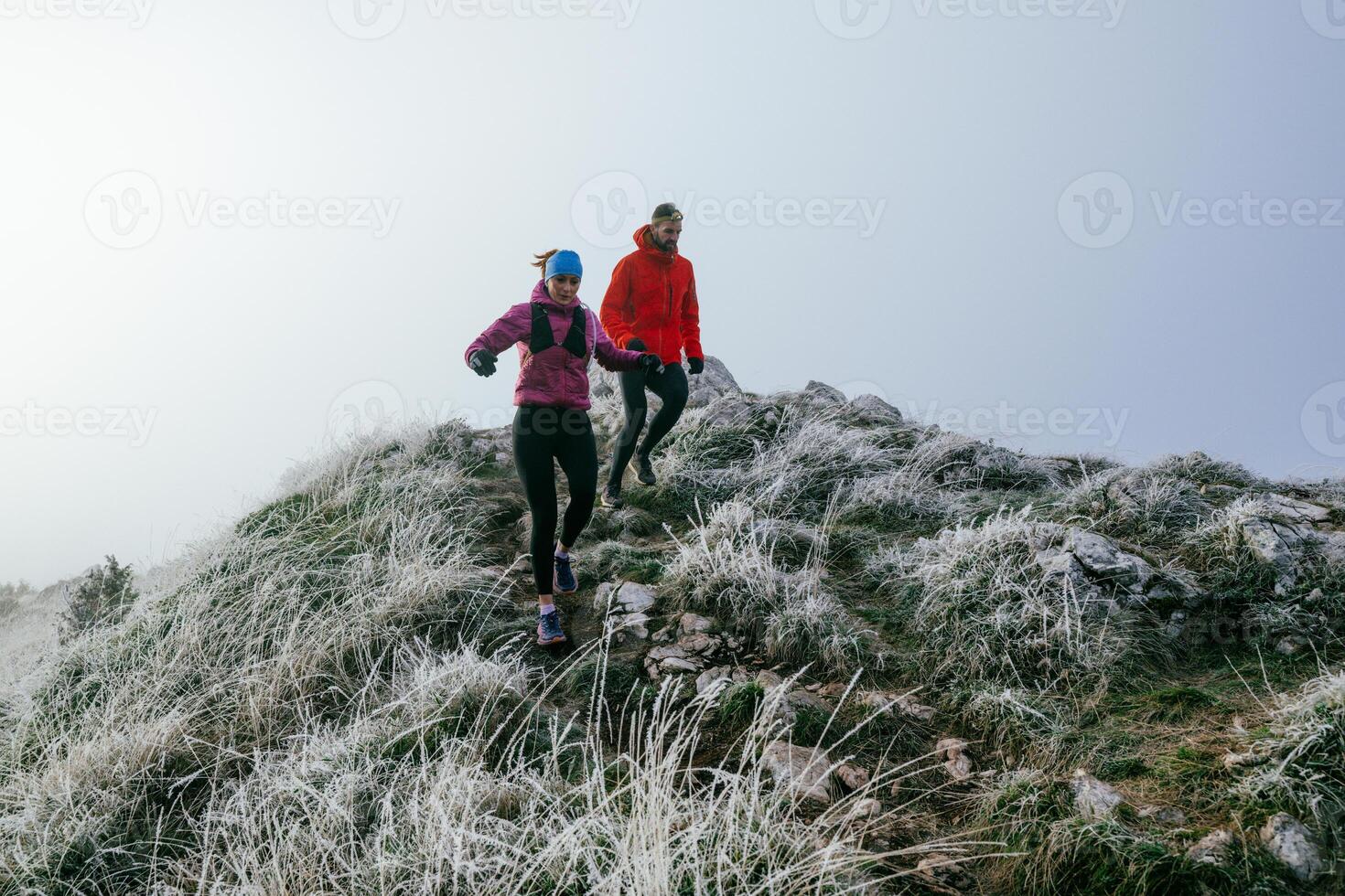 Trail running couple man and woman running on a mountain path photo