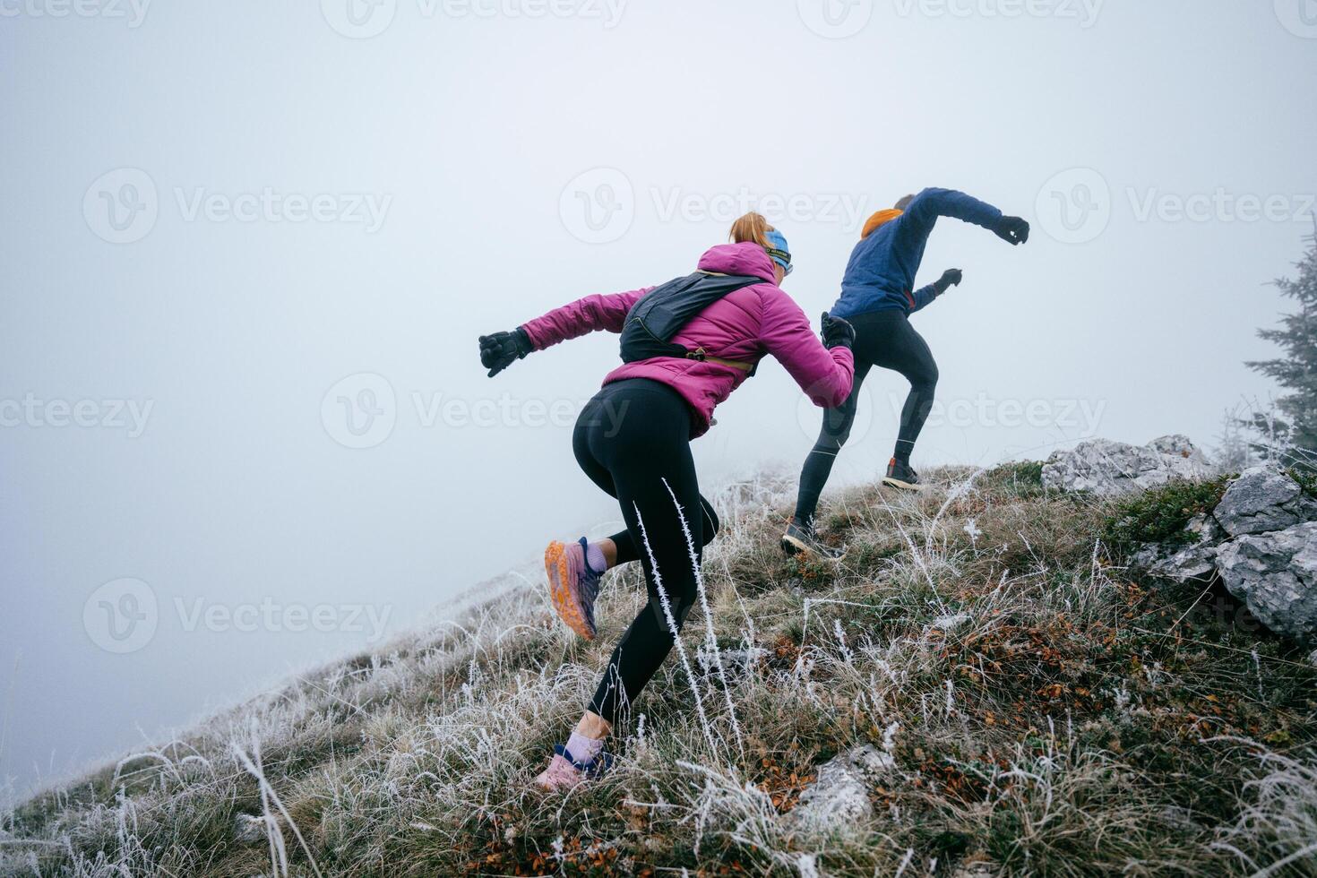 Trail running couple man and woman running on a mountain path photo
