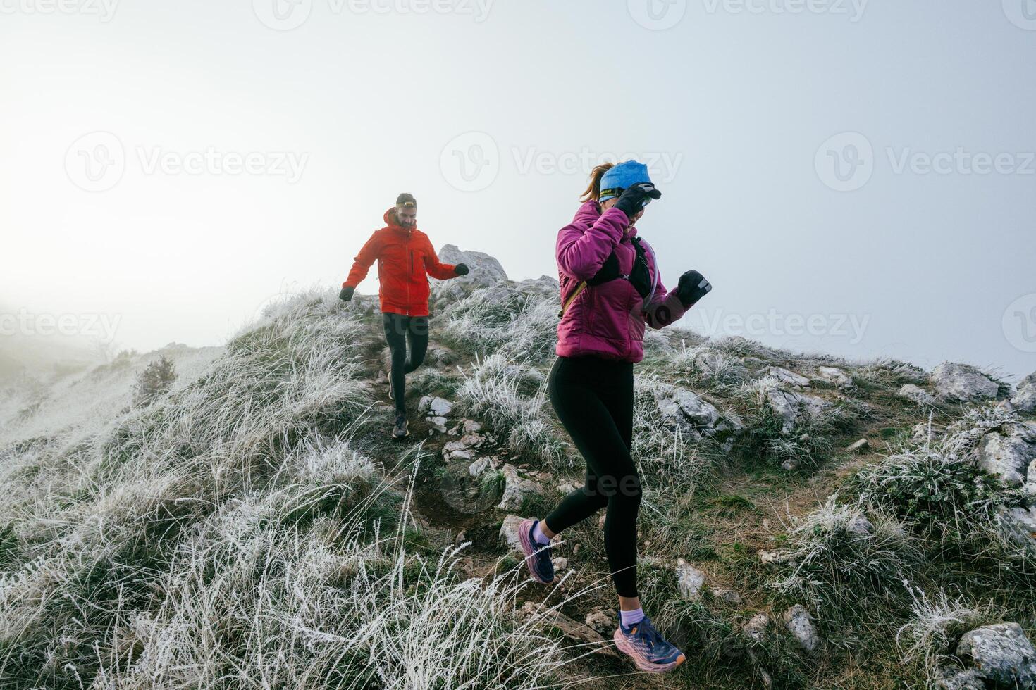 Trail running couple man and woman running on a mountain path photo