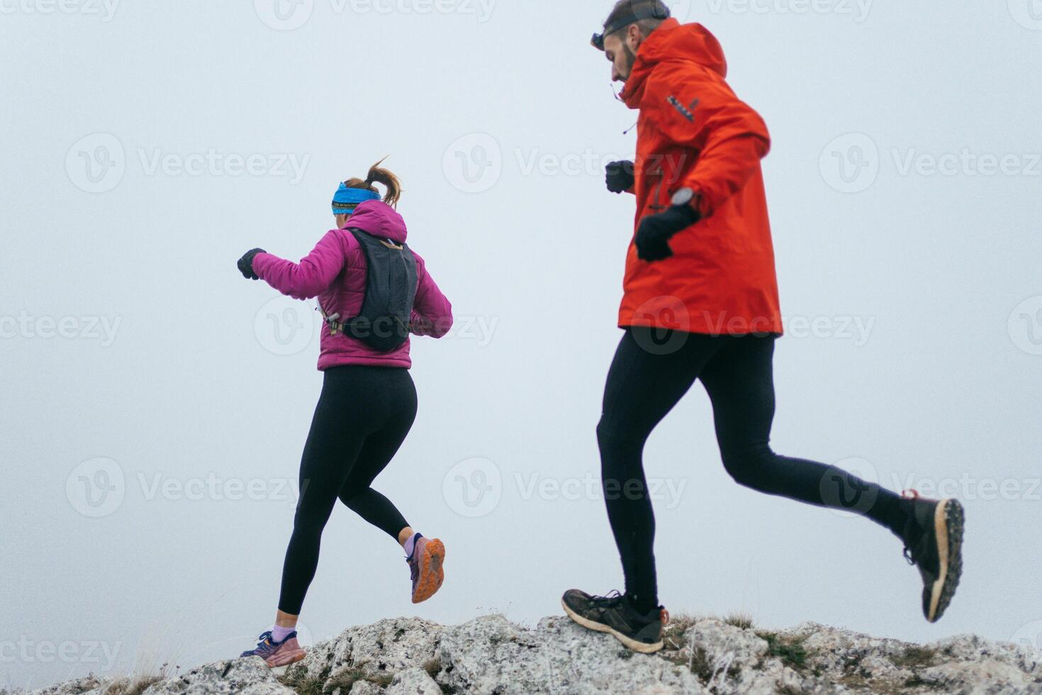 Trail running couple man and woman running on a mountain path photo