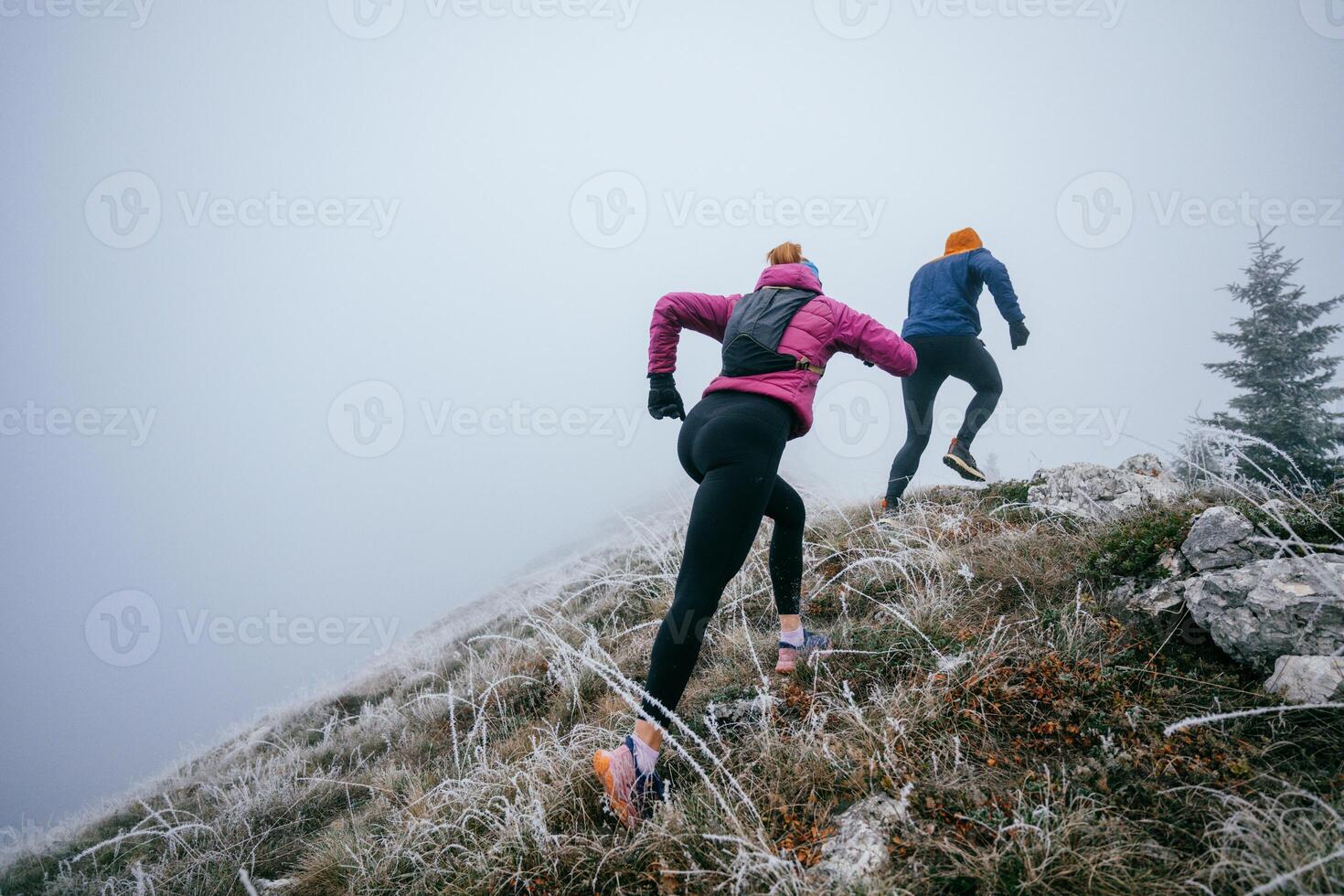 Trail running couple man and woman running on a mountain path photo