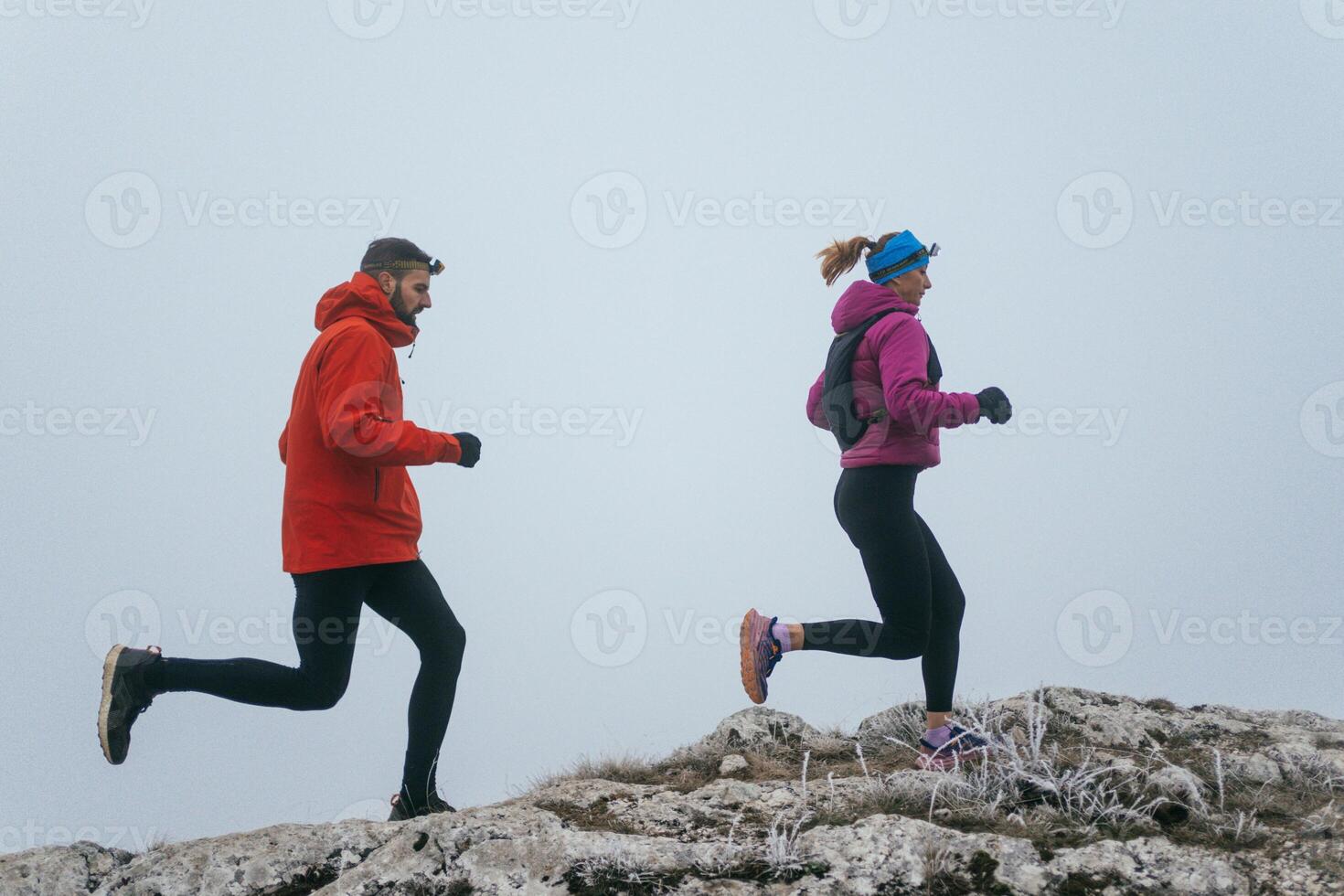 Trail running couple man and woman running on a mountain path photo