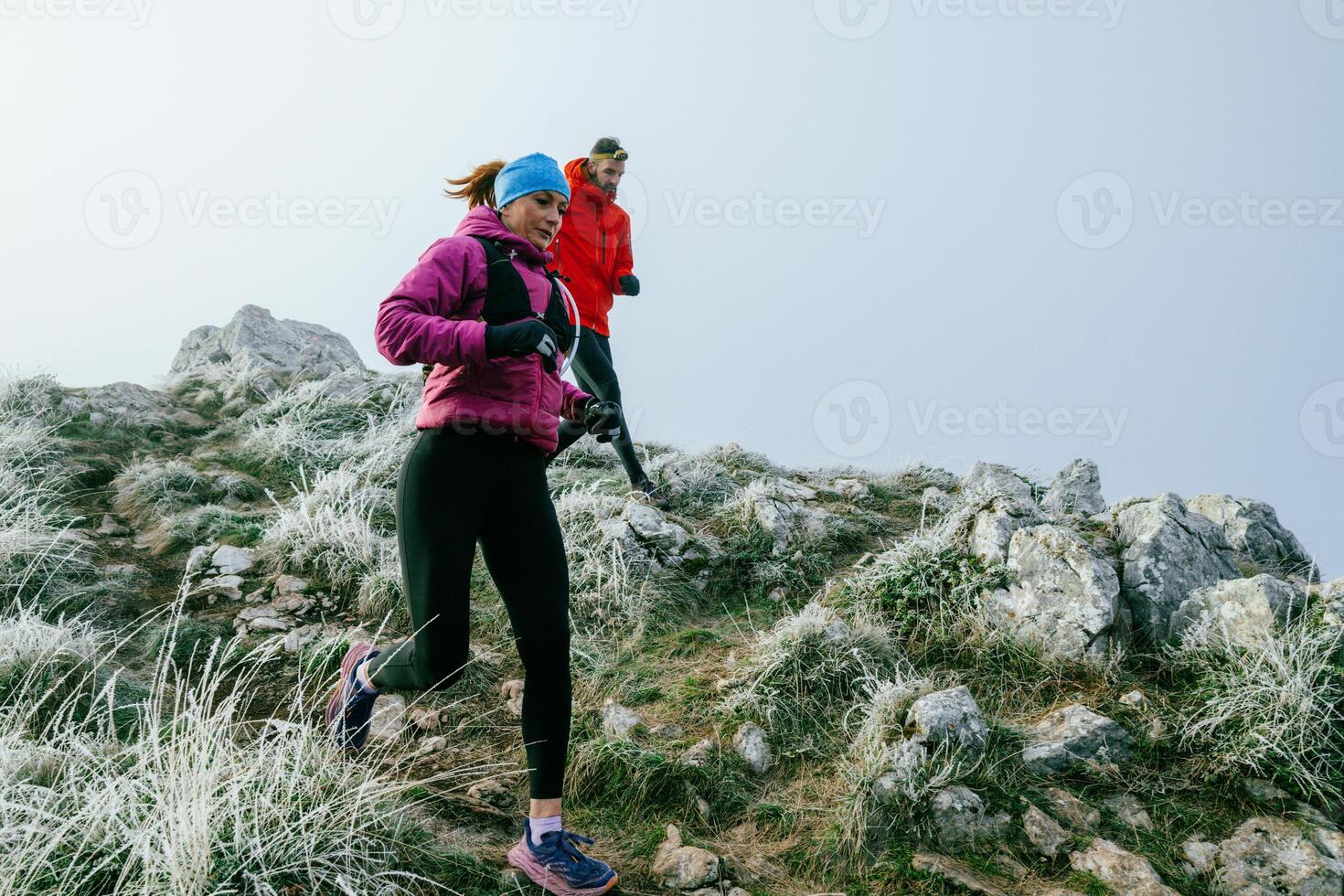 Trail running couple man and woman running on a mountain path photo