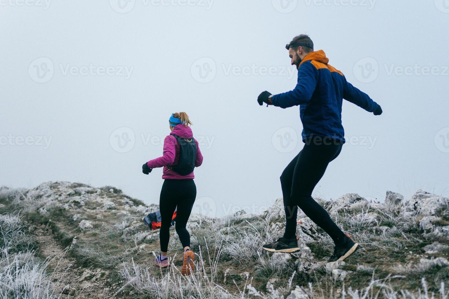 Trail running couple man and woman running on a mountain path photo