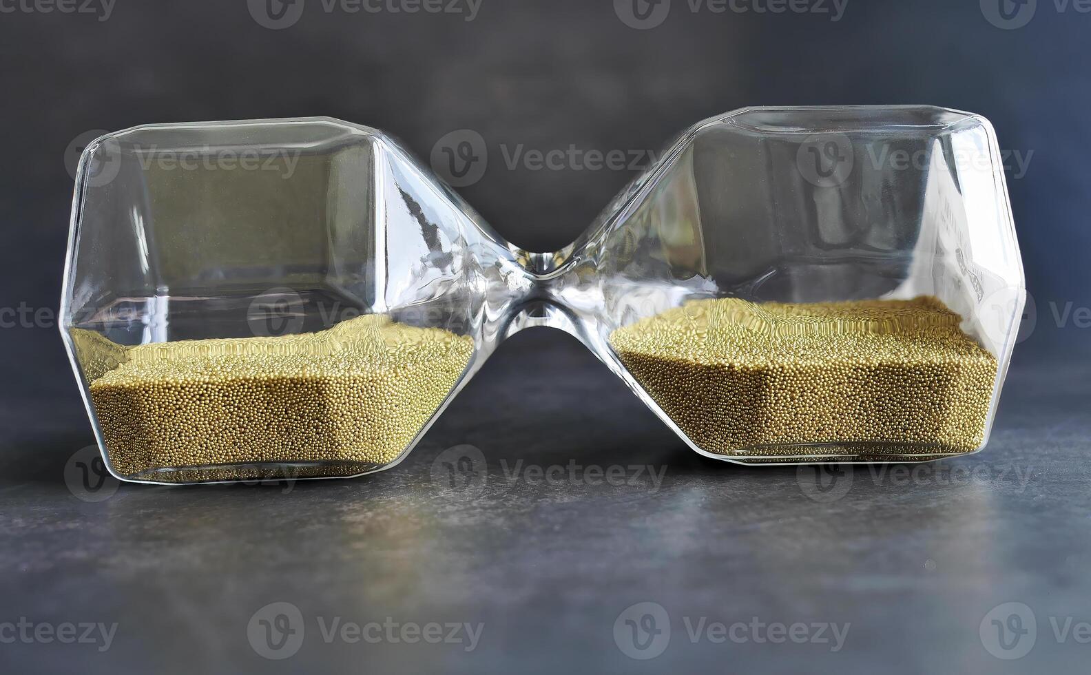 Laying sideway transparent Hourglass with golden Sand, sand glass in dark background, Time Stop or balance time concept, for advertising photo