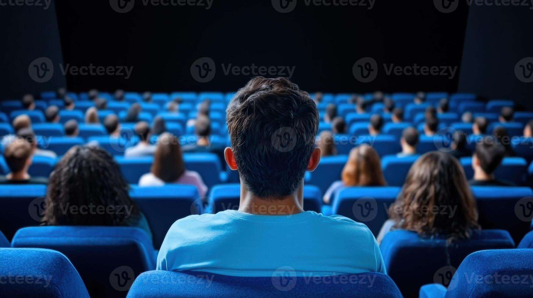 A group of people sitting in a cinema watching a movie, with a focus on the back of their heads, creating a sense of community. photo