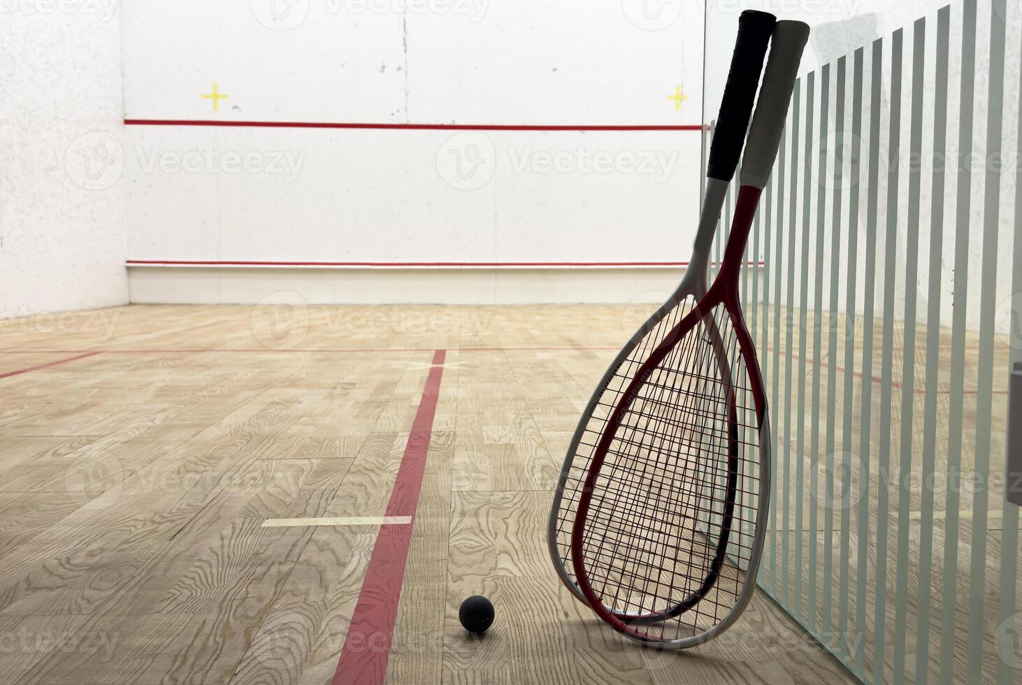 Two rackets and two squash balls lie on the parquet floor. Horizontal photo