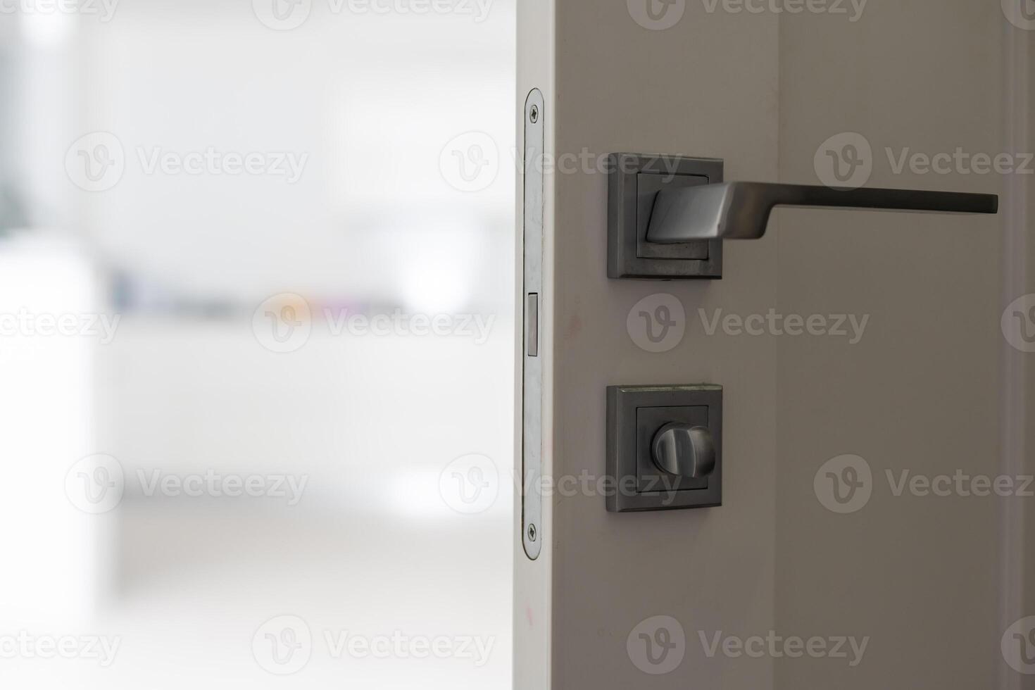 Chrome handle with keyhole on white door with panels in frames. Entrance. Close-up photo of architecture detail. Interior fragment as geometrical background with three rectangles and parallel lines