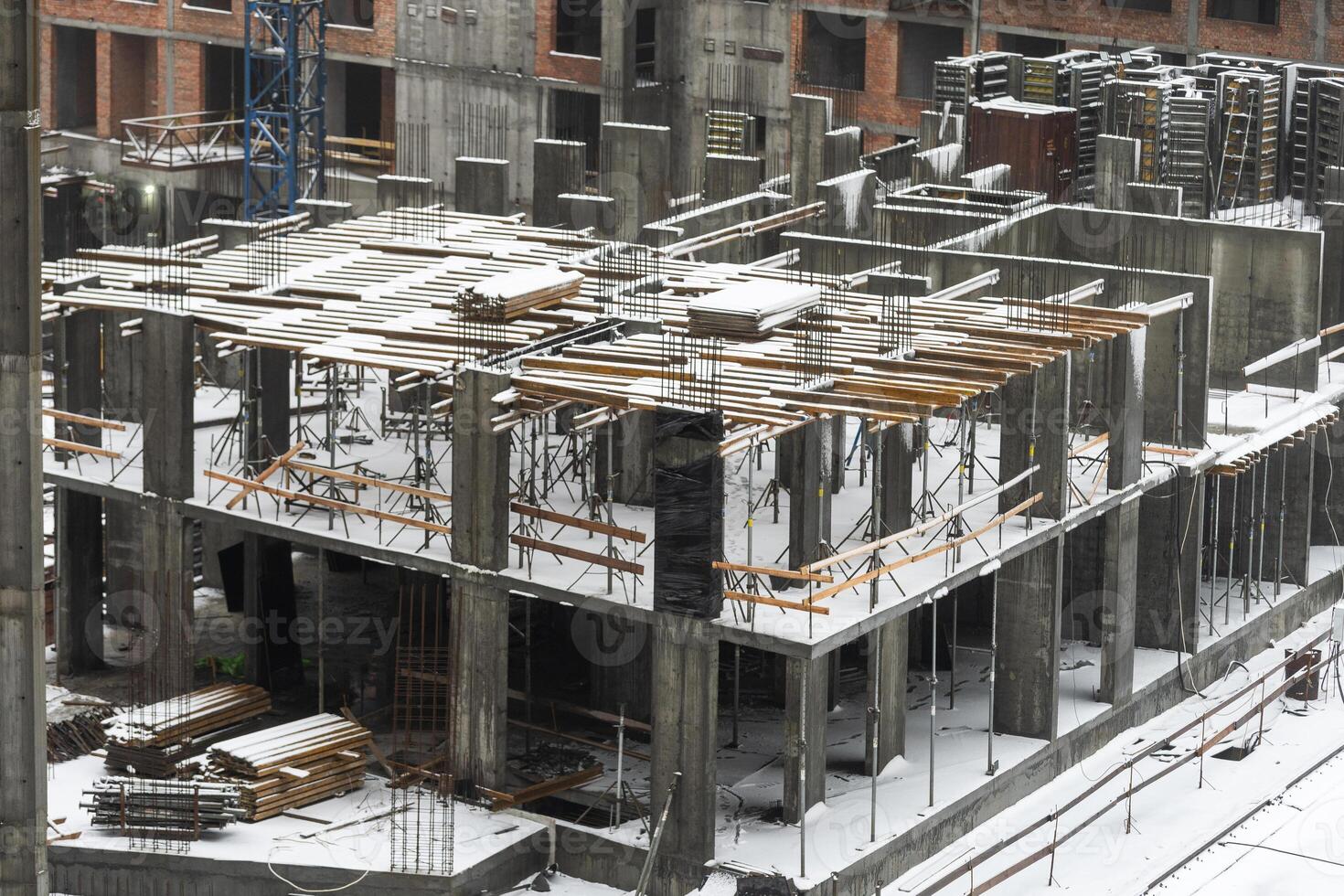 clogged piles in the foreground of a new house under construction in winter against the background of a crane photo