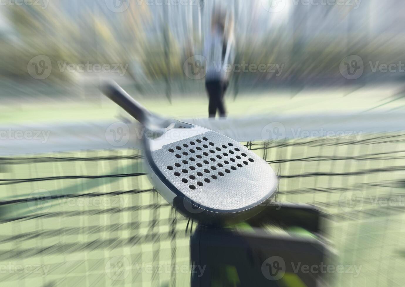 A padel or paddle tennis racket and a bright yellow tennis ball lie on a blue court. photo