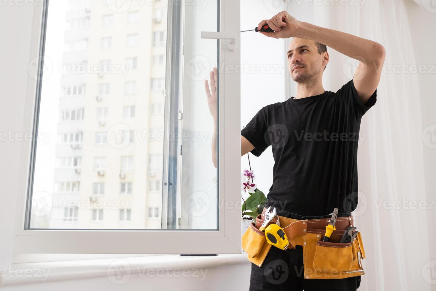 Master in gloves adjusting pvc windows with screwdriver closeup. Installation of plastic windows repair and maintenance concept photo