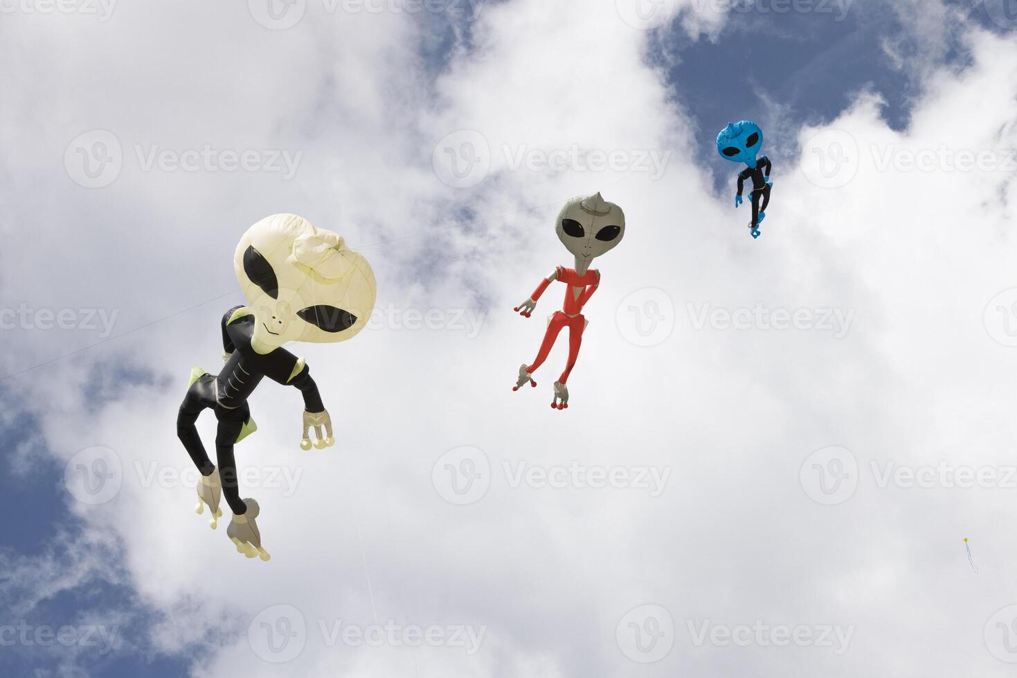 Alien-shaped balloons floating against a blue sky with clouds, creating a fun and whimsical atmosphere. photo