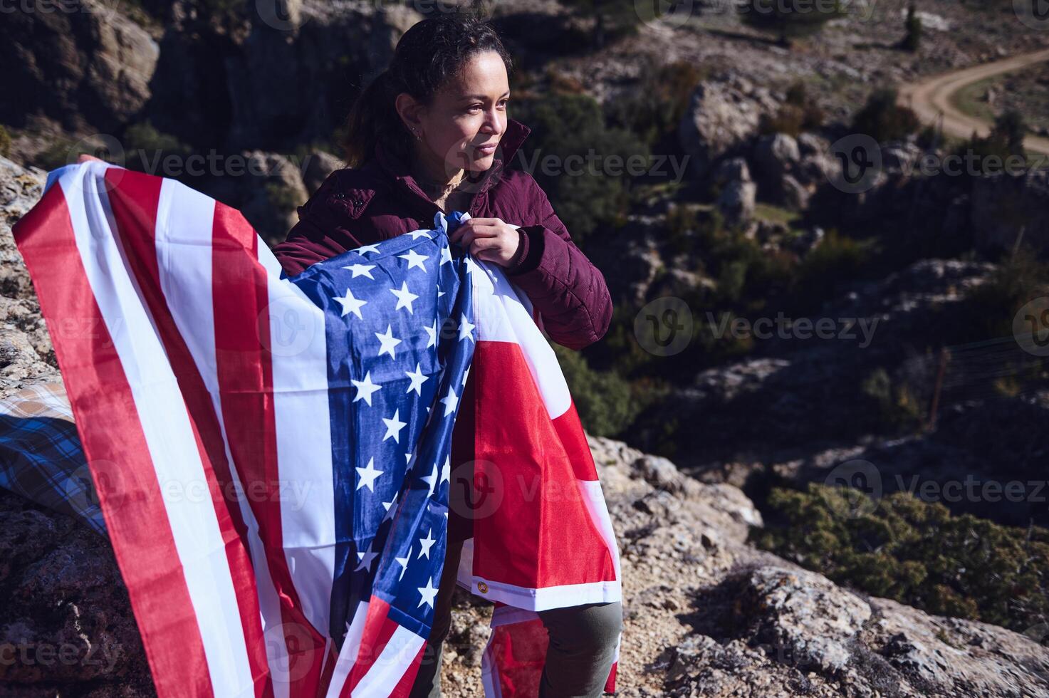 Woman outdoors holding an American flag with mountains in the background photo