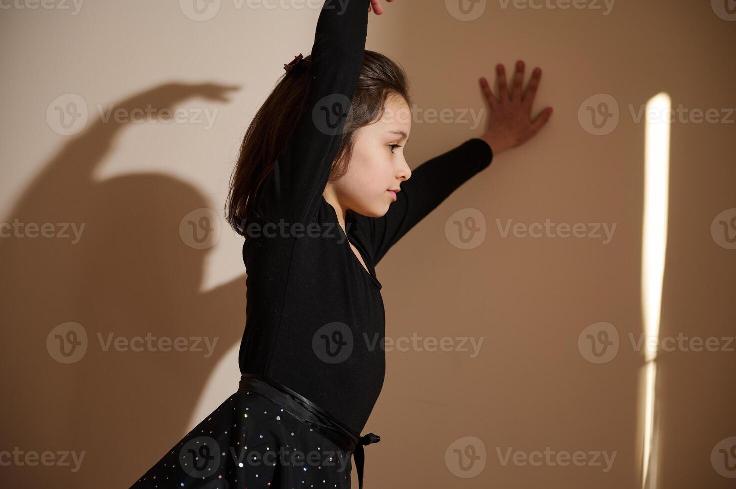 Young girl practicing graceful dance movements in a brightly lit room photo