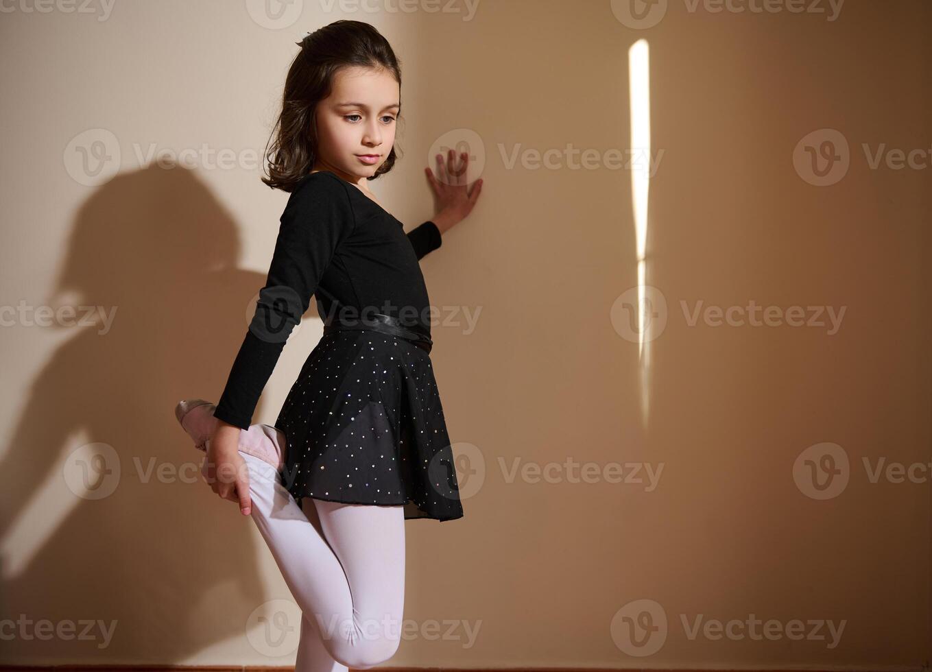 Young girl in dance pose wearing a black outfit in a lit room photo